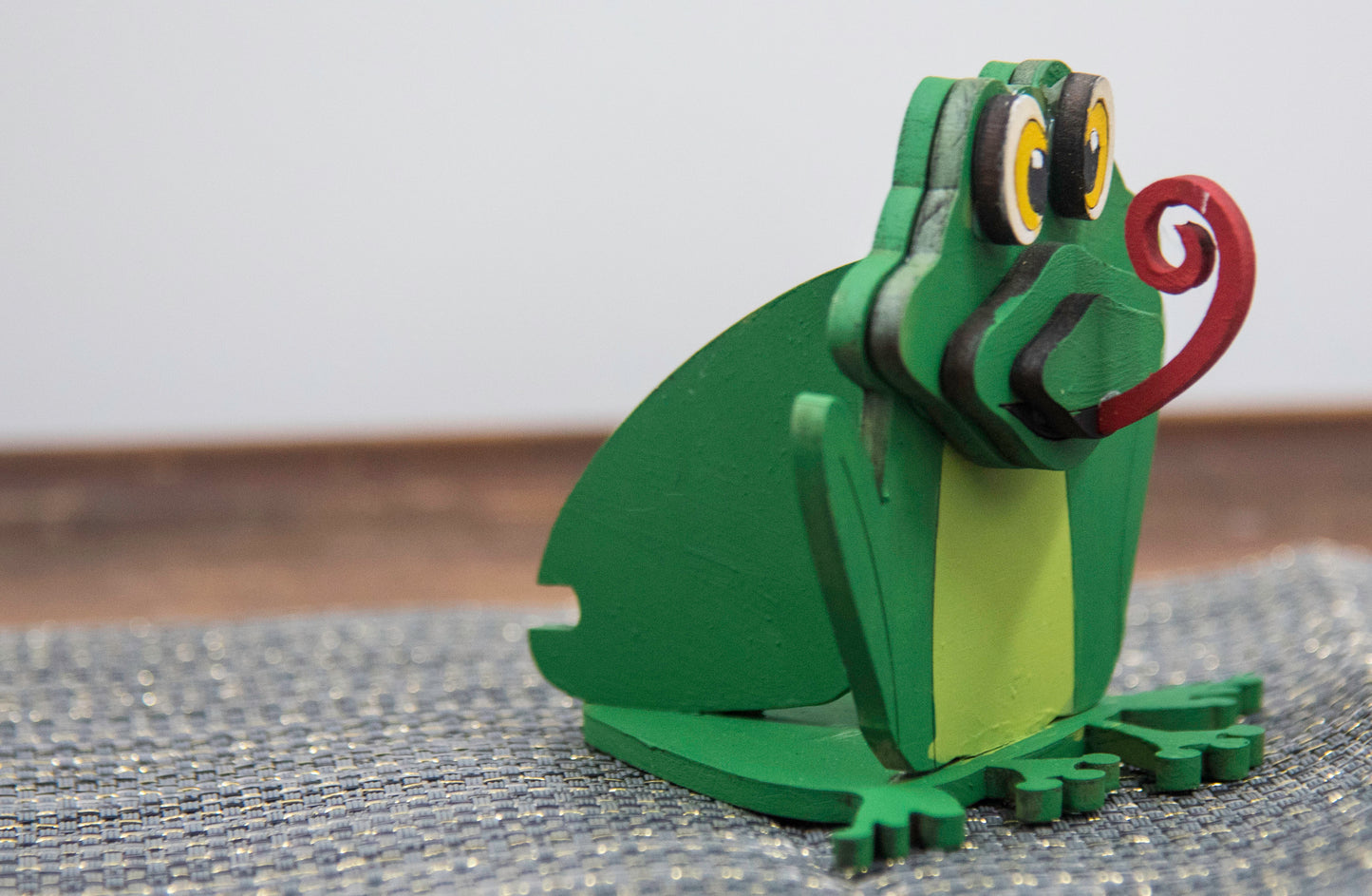 Hand-painted wooden frog-shaped glasses holder with bulging eyes and a flat base to hold eyeglasses. Ideal for desks, nightstands, or gifting to frog lovers and animal fans