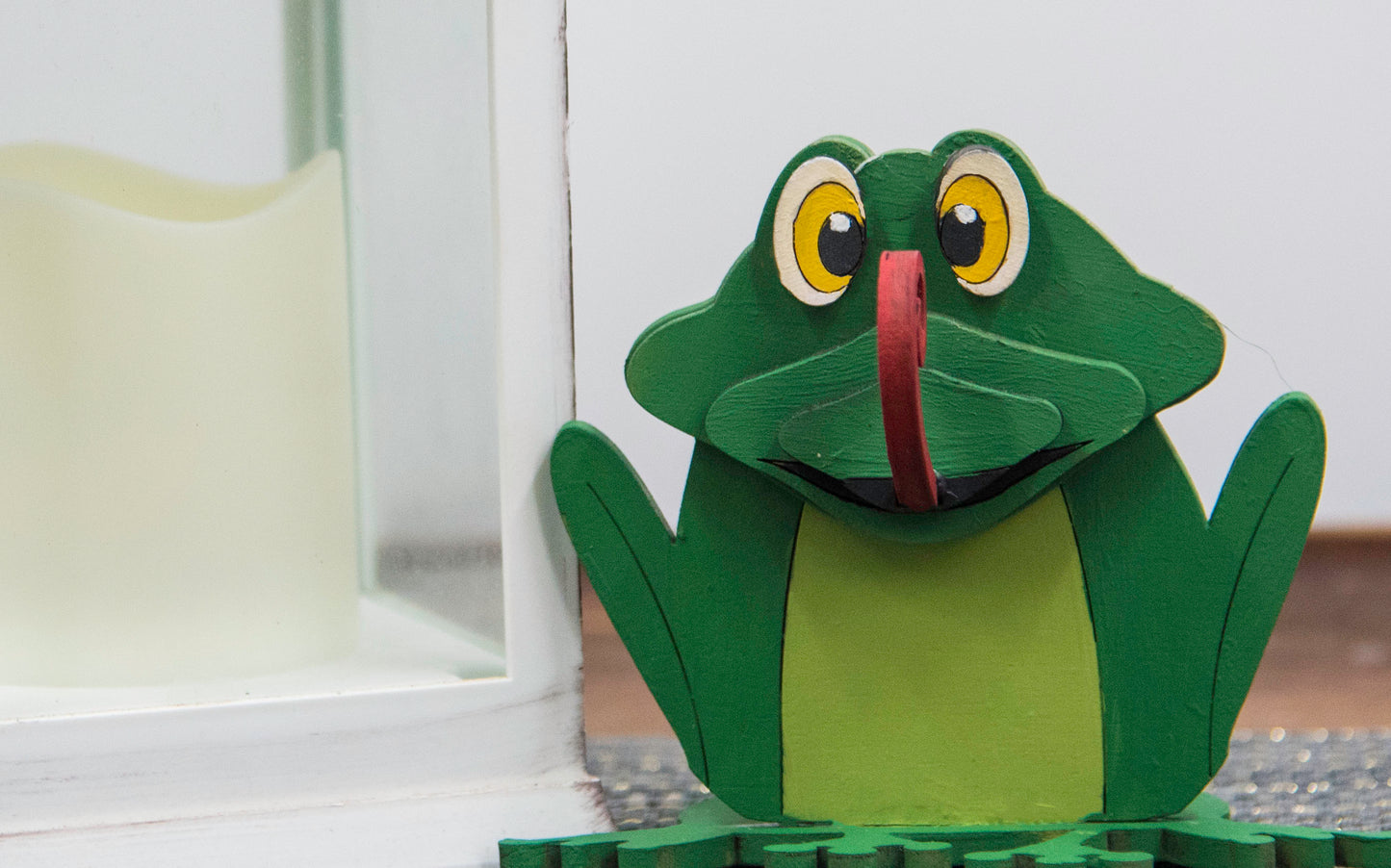 Hand-painted wooden frog-shaped glasses holder with bulging eyes and a flat base to hold eyeglasses. Ideal for desks, nightstands, or gifting to frog lovers and animal fans