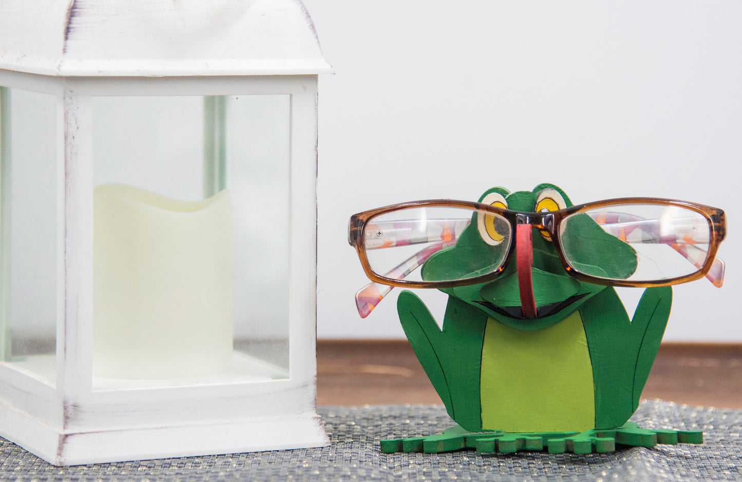 Hand-painted wooden frog-shaped glasses holder with bulging eyes and a flat base to hold eyeglasses. Ideal for desks, nightstands, or gifting to frog lovers and animal fans
