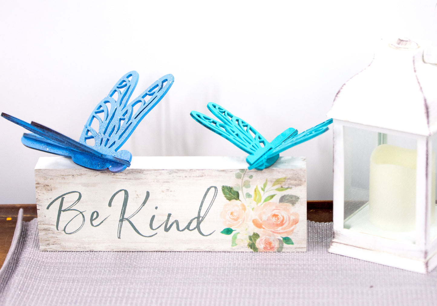Colorful wooden dragonfly shelf sitters in rustic painted finishes, each shaped with wings and body details, perfect for whimsical spring or summer decor on mantels, shelves, or tiered trays.