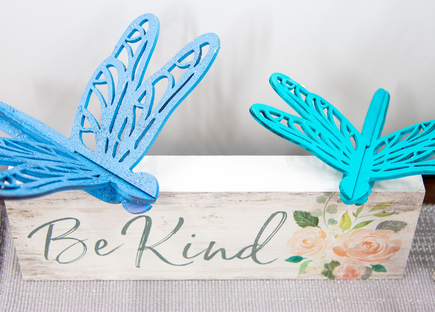 Colorful wooden dragonfly shelf sitters in rustic painted finishes, each shaped with wings and body details, perfect for whimsical spring or summer decor on mantels, shelves, or tiered trays.