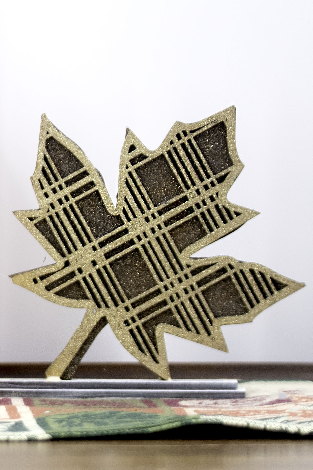 Handcrafted standing wooden leaf decor pieces in layered colors and patterns. Each leaf has a stained background with a cutout patterned top layer, sitting on a flat wood base. Ideal for fall or farmhouse-style decor