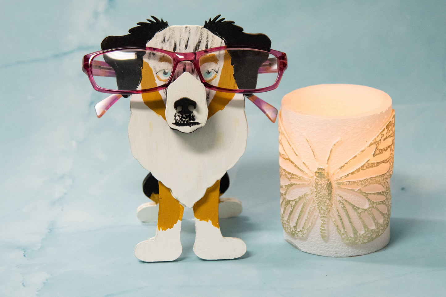 Hand-painted Australian Shepherd eyeglass holder in a sitting dog shape, available in Blue Merle, Red Merle, Black Tri, or custom colors with realistic details, designed to hold glasses on the snout. Cute and functional dog lover gift, hand-crafted and great for desks or nightstands.