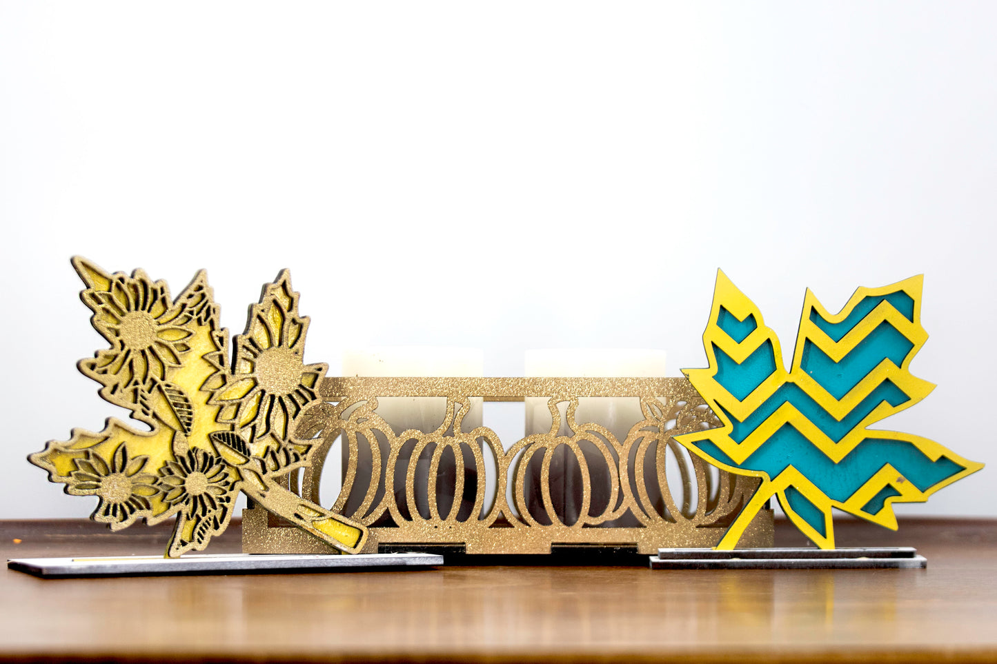 Set of freestanding wooden leaf shelf sitters with two-layer designs, featuring colorful stained bases and patterned top cutouts in fall-themed shapes. These decorative leaves range in size from 3" to 6" tall and are ideal for mantels, tiered trays, and autumn home displays. Handcrafted, rustic, and available in custom colors. Perfect for fall decorating, Thanksgiving accents, and cozy seasonal vibes.