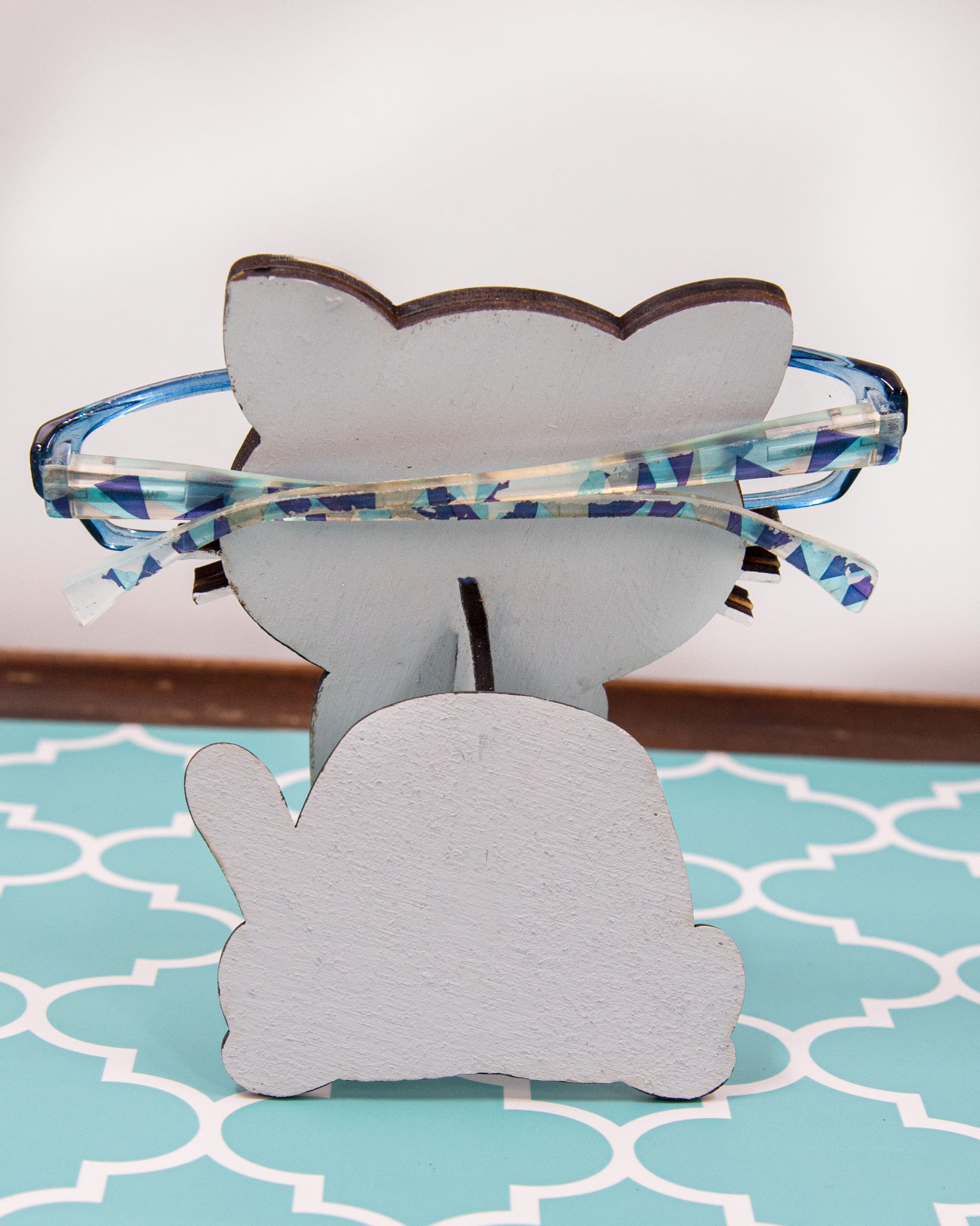 Custom-painted wooden cat glasses holder shaped like a sitting cat with eyeglasses resting on its nose. Available in black, white, orange, gray, tabby, Siamese, tuxedo, or painted from your cat's photo with optional name personalization.