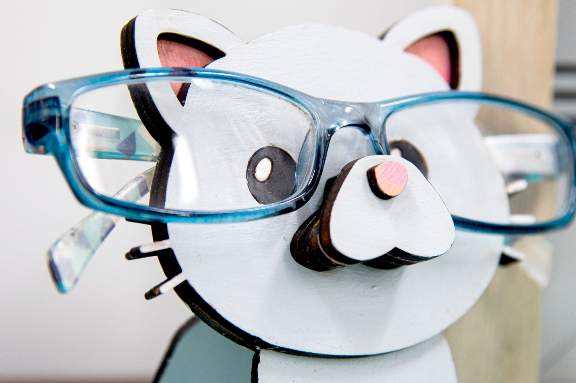 Custom-painted wooden cat glasses holder shaped like a sitting cat with eyeglasses resting on its nose. Available in black, white, orange, gray, tabby, Siamese, tuxedo, or painted from your cat's photo with optional name personalization.