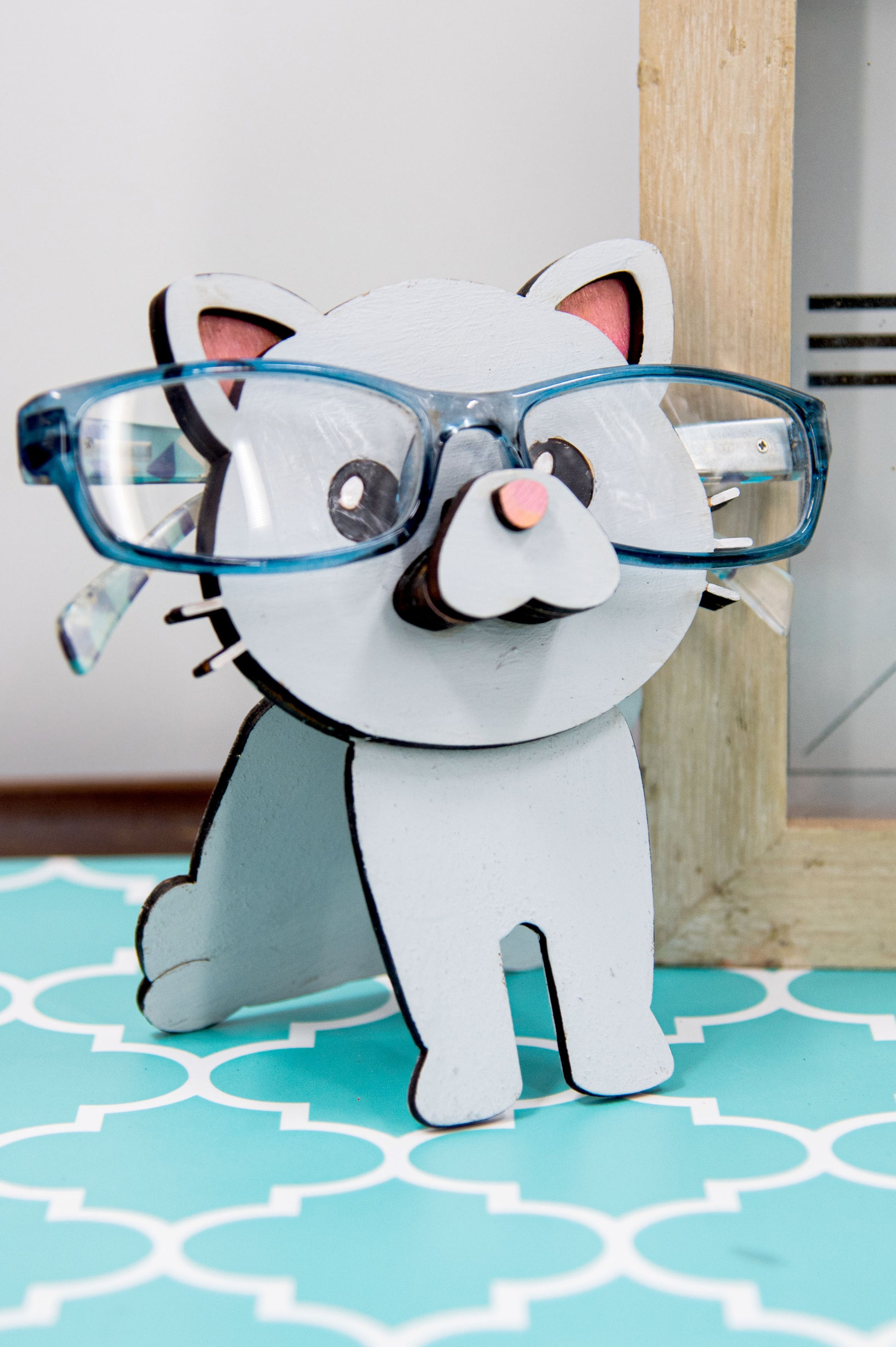 Custom-painted wooden cat glasses holder shaped like a sitting cat with eyeglasses resting on its nose. Available in black, white, orange, gray, tabby, Siamese, tuxedo, or painted from your cat's photo with optional name personalization.