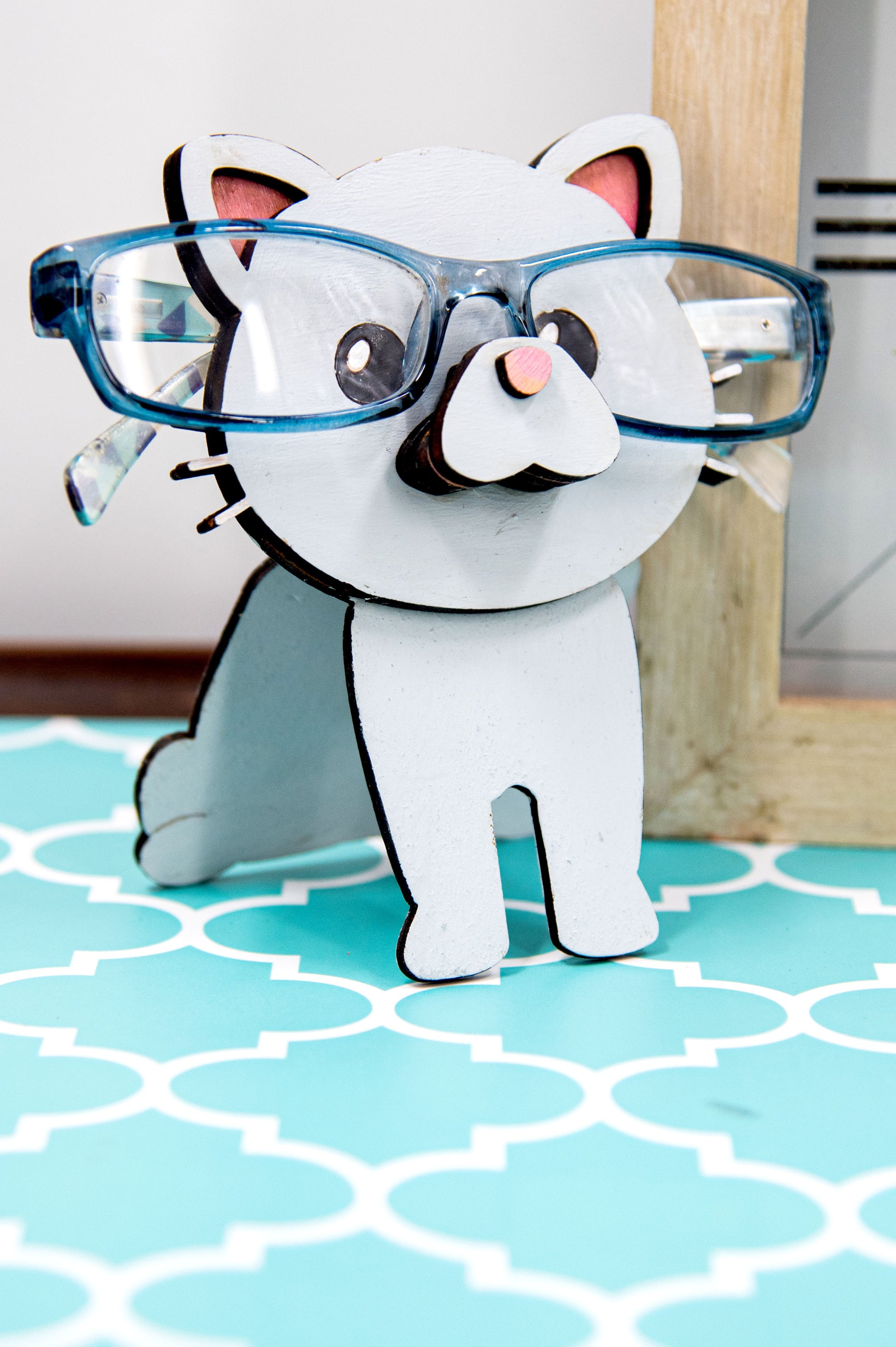 Custom-painted wooden cat glasses holder shaped like a sitting cat with eyeglasses resting on its nose. Available in black, white, orange, gray, tabby, Siamese, tuxedo, or painted from your cat's photo with optional name personalization.