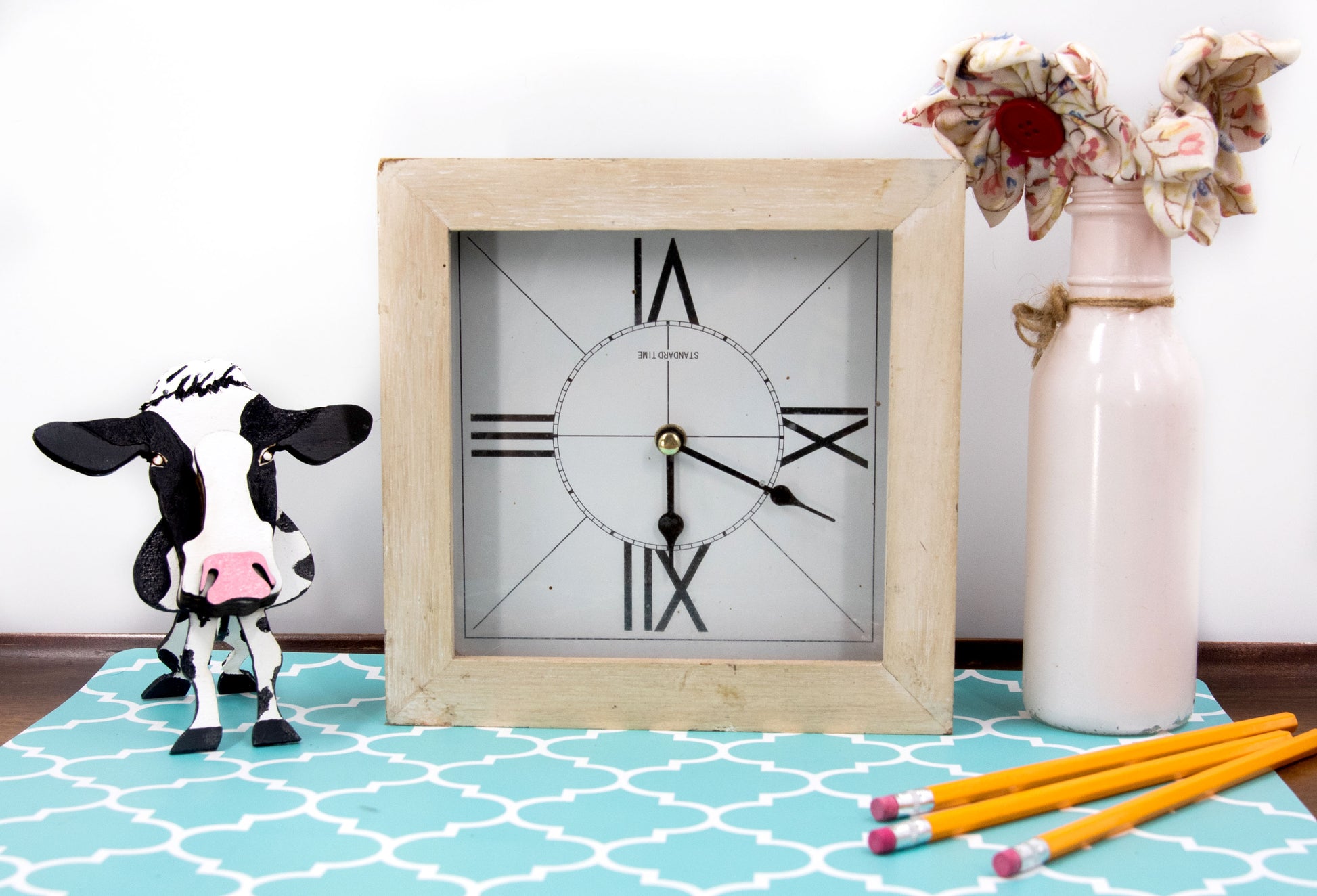 Wooden cow-shaped glasses holder, painted black and white with a layered design, holding a pair of eyeglasses, ideal for farm animal lovers and rustic decor.
