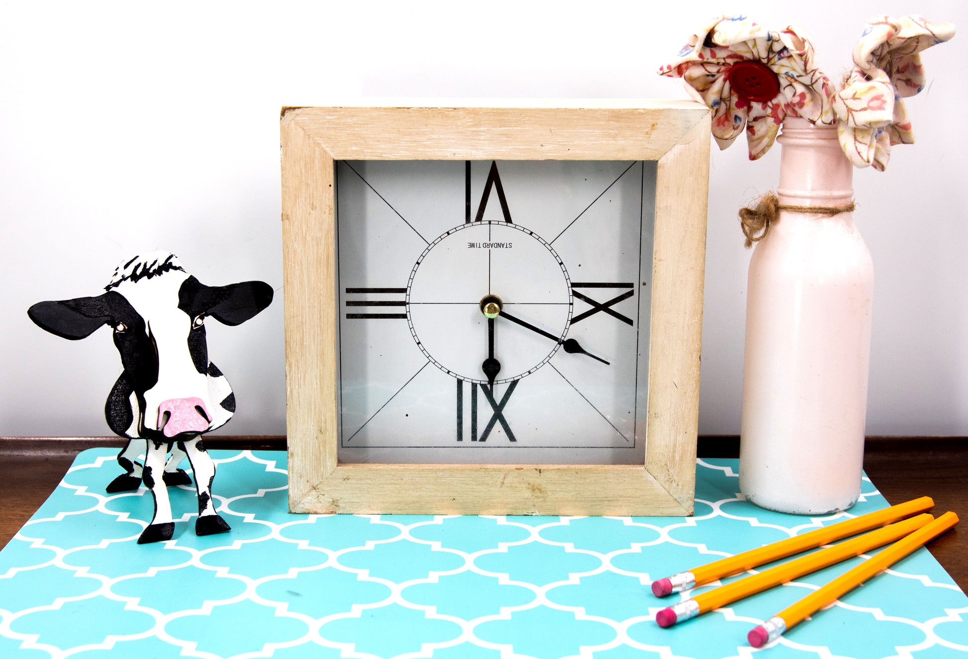 Wooden cow-shaped glasses holder, painted black and white with a layered design, holding a pair of eyeglasses, ideal for farm animal lovers and rustic decor.
