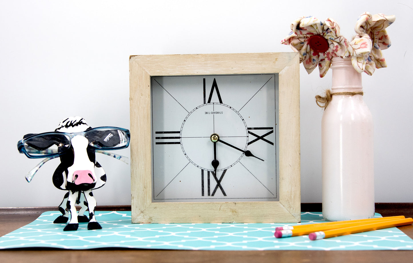 Wooden cow-shaped glasses holder, painted black and white with a layered design, holding a pair of eyeglasses, ideal for farm animal lovers and rustic decor.
