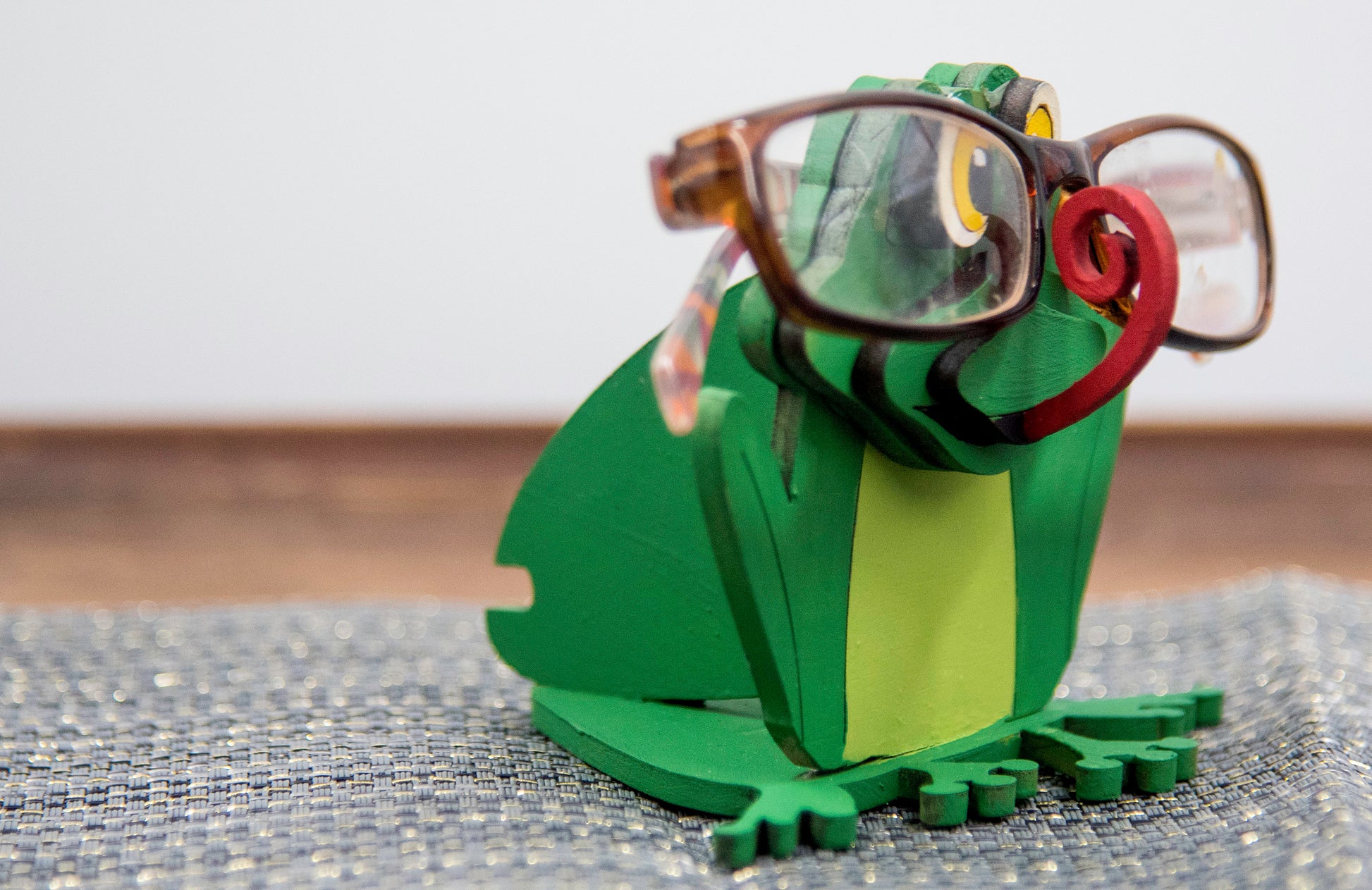 Hand-painted wooden frog-shaped glasses holder with bulging eyes and a flat base to hold eyeglasses. Ideal for desks, nightstands, or gifting to frog lovers and animal fans