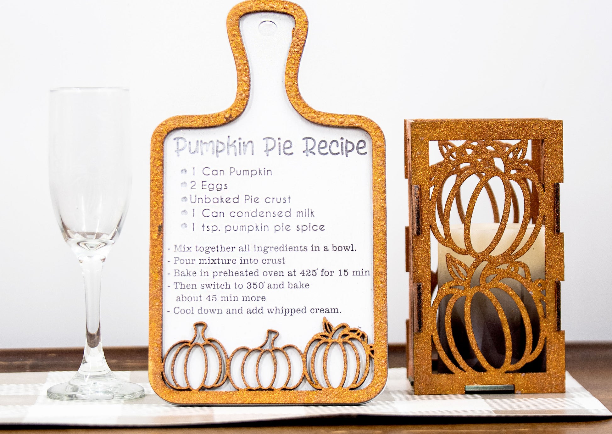 Laser-cut wooden cutting board with engraved pumpkin pie recipe and decorative pumpkins, styled on a fall plaid table runner with pumpkins and wine glass.
