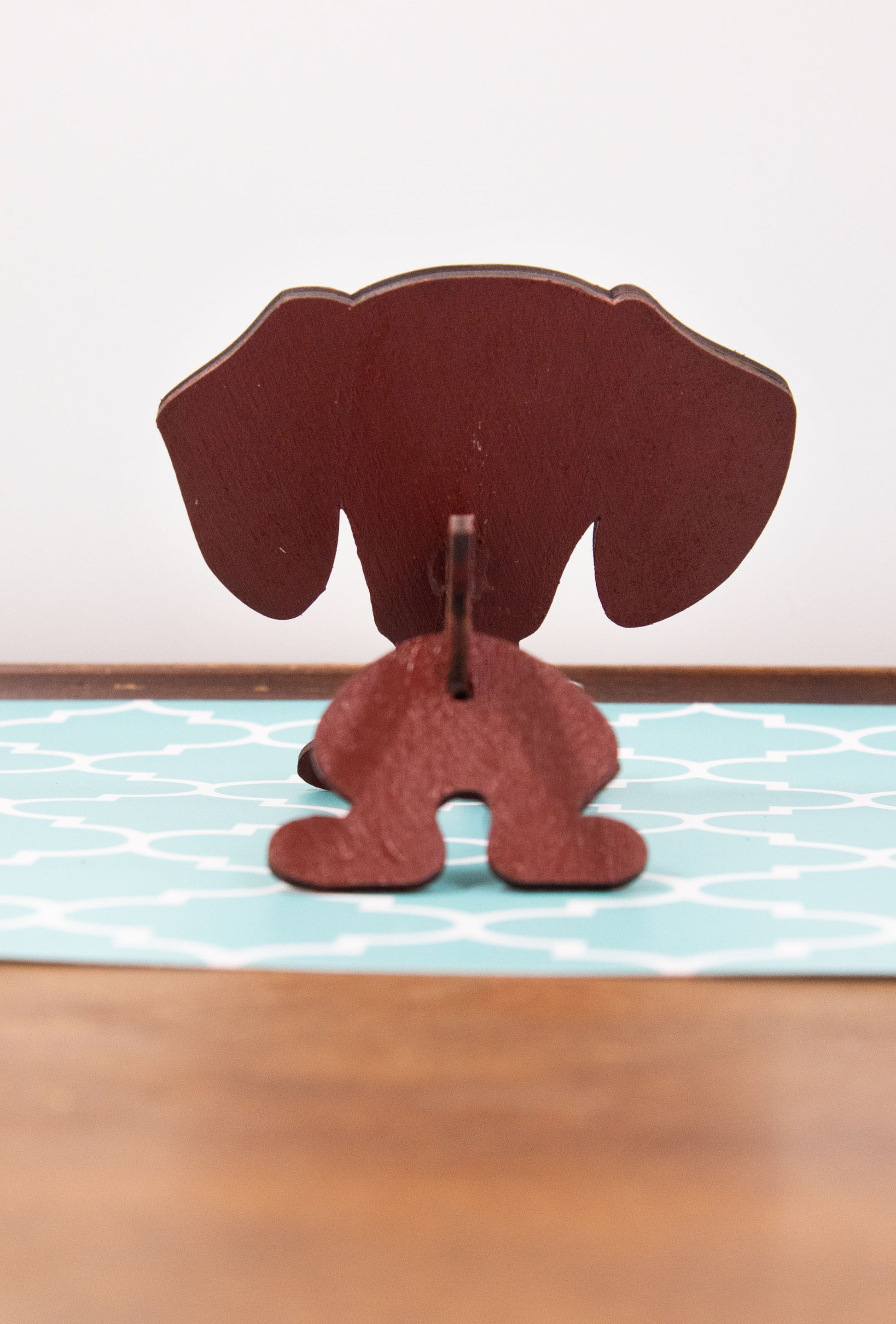 Handcrafted small wooden glasses holder in the shape of a Dachshund, featuring a painted dog design with carved detail and a curved snout to hold eyeglasses securely. A compact and charming gift for dog lovers, especially fans of wiener dogs, and perfect for display on a nightstand, office desk, or bookshelf.