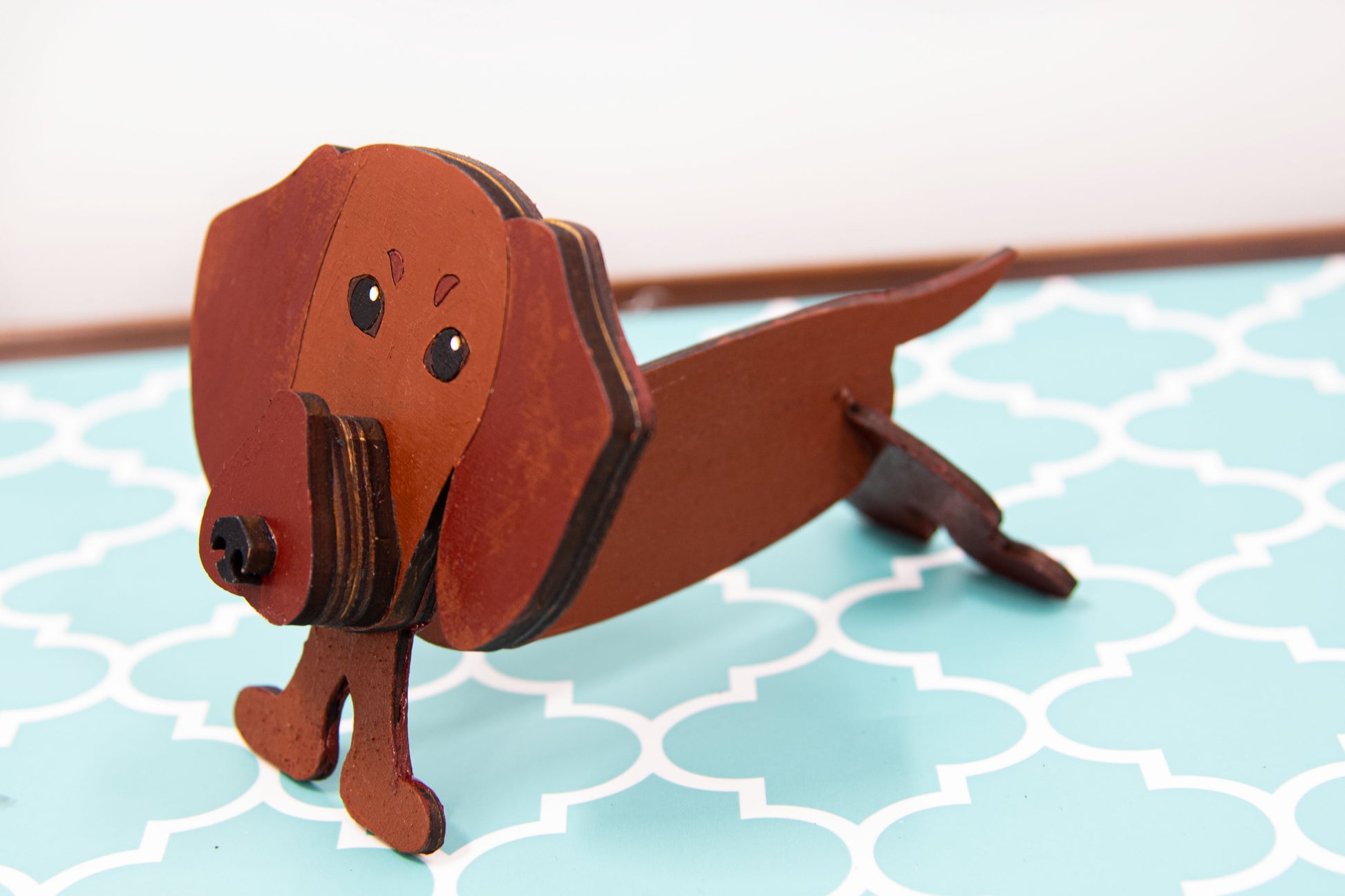 Handcrafted small wooden glasses holder in the shape of a Dachshund, featuring a painted dog design with carved detail and a curved snout to hold eyeglasses securely. A compact and charming gift for dog lovers, especially fans of wiener dogs, and perfect for display on a nightstand, office desk, or bookshelf.