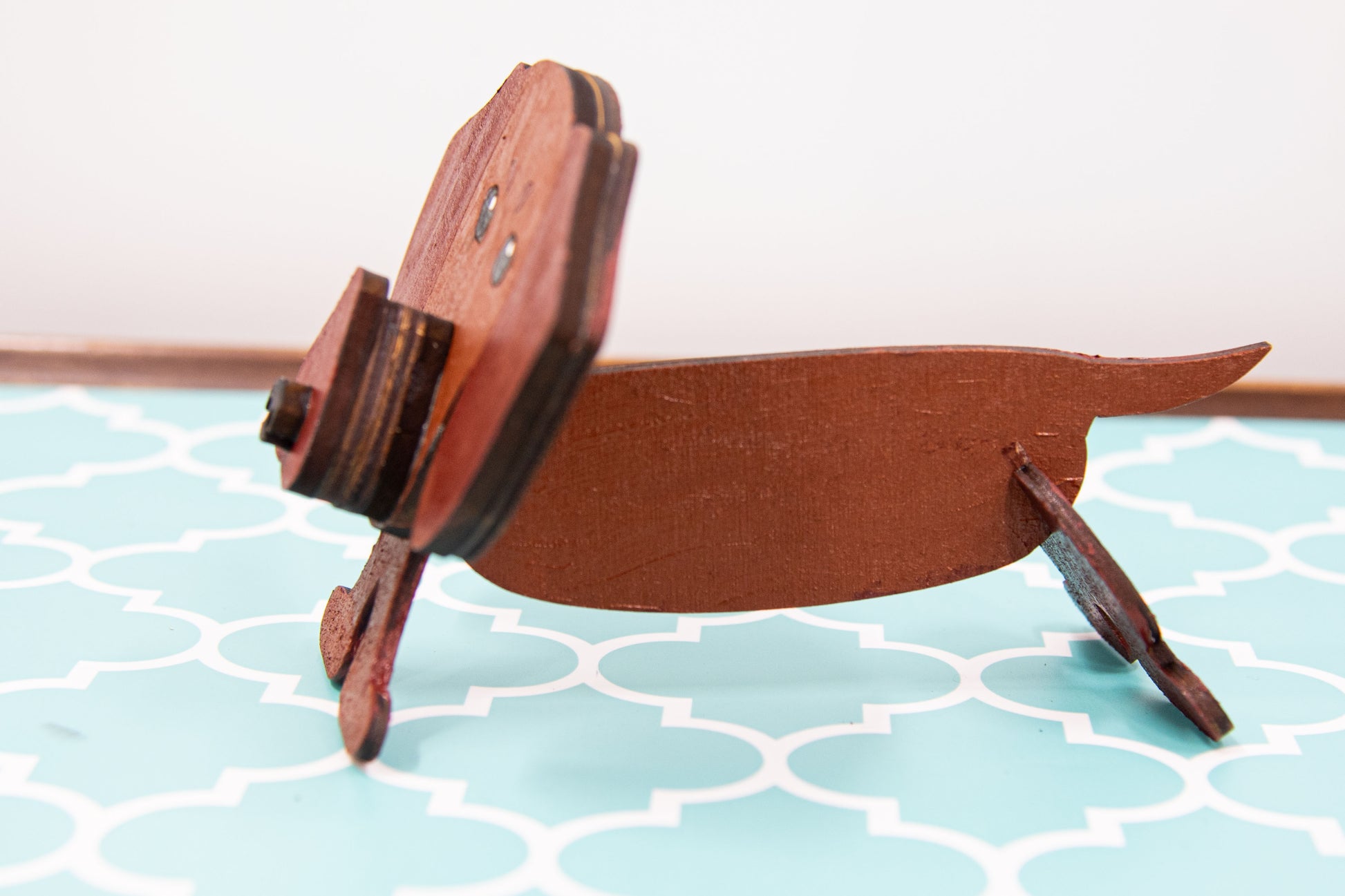 Handcrafted small wooden glasses holder in the shape of a Dachshund, featuring a painted dog design with carved detail and a curved snout to hold eyeglasses securely. A compact and charming gift for dog lovers, especially fans of wiener dogs, and perfect for display on a nightstand, office desk, or bookshelf.