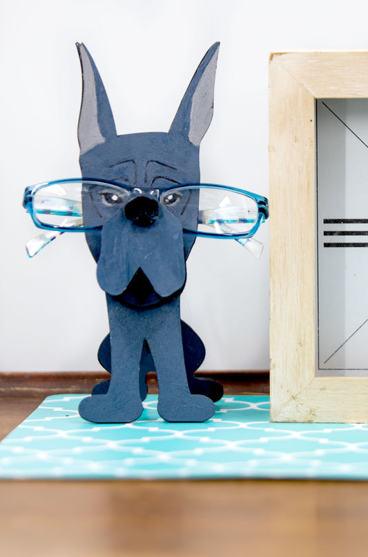 A handcrafted wooden Great Dane eyeglasses holder designed to resemble the iconic breed, available with floppy or docked ears. Comes in black, blue, fawn, or detailed mantle coloring. Floppy ear version measures 6.35" tall by 4.35" wide; docked ear version stands 8.5" tall by 3.15" wide. Perfect for organizing glasses on desks or nightstands, and makes a great gift for Great Dane lovers.