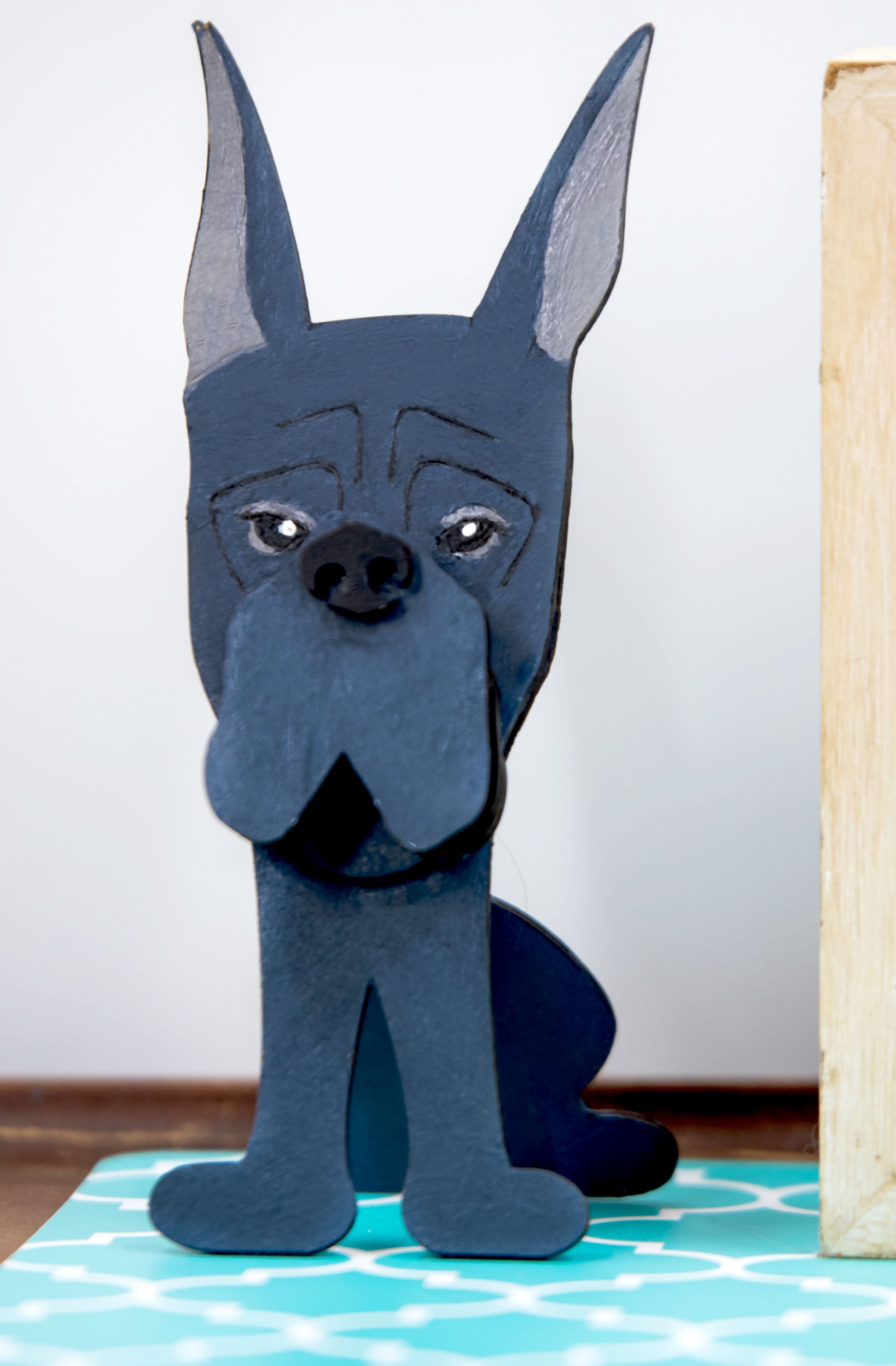A handcrafted wooden Great Dane eyeglasses holder designed to resemble the iconic breed, available with floppy or docked ears. Comes in black, blue, fawn, or detailed mantle coloring. Floppy ear version measures 6.35" tall by 4.35" wide; docked ear version stands 8.5" tall by 3.15" wide. Perfect for organizing glasses on desks or nightstands, and makes a great gift for Great Dane lovers.
