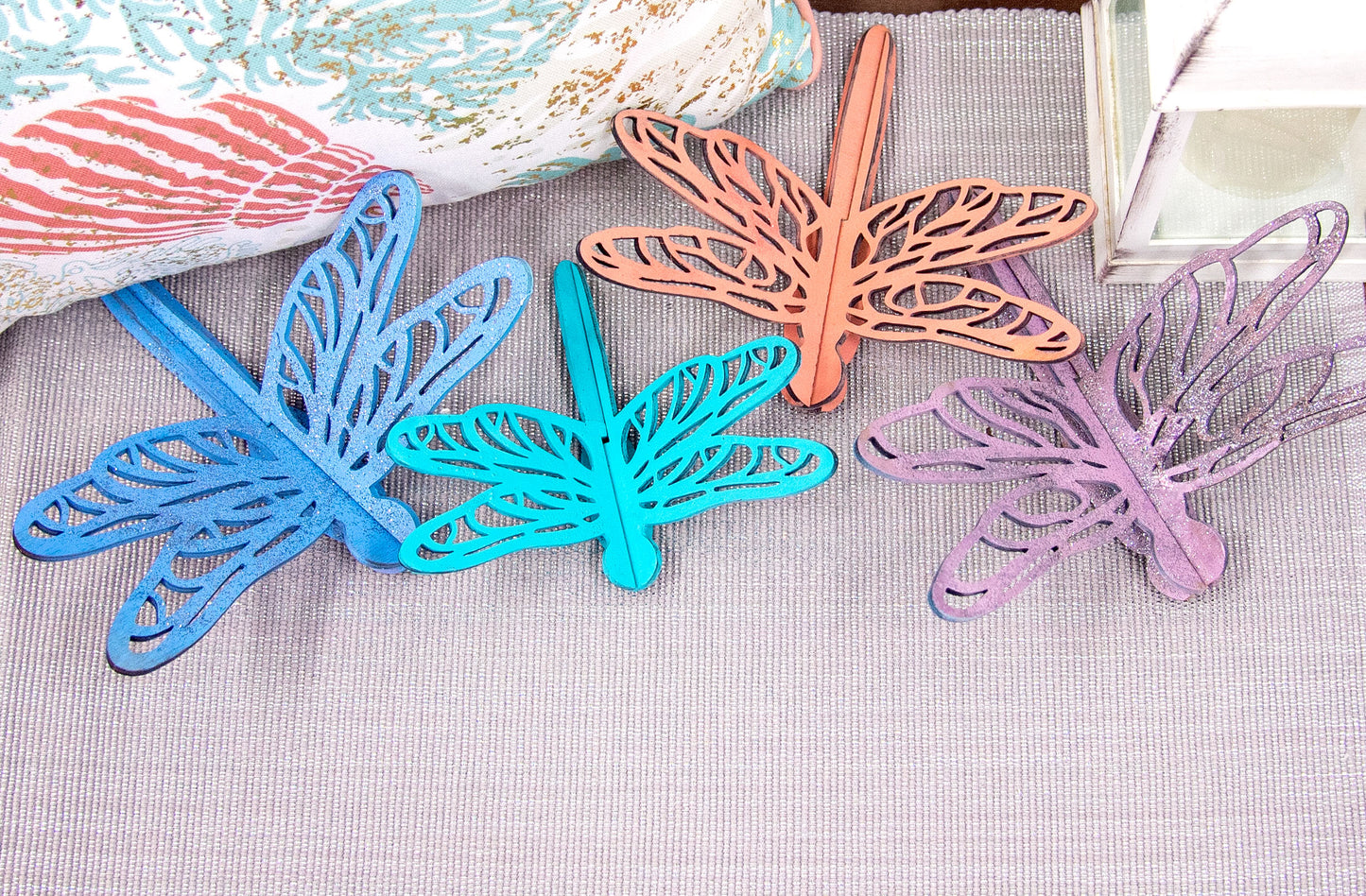 Colorful wooden dragonfly shelf sitters in rustic painted finishes, each shaped with wings and body details, perfect for whimsical spring or summer decor on mantels, shelves, or tiered trays.