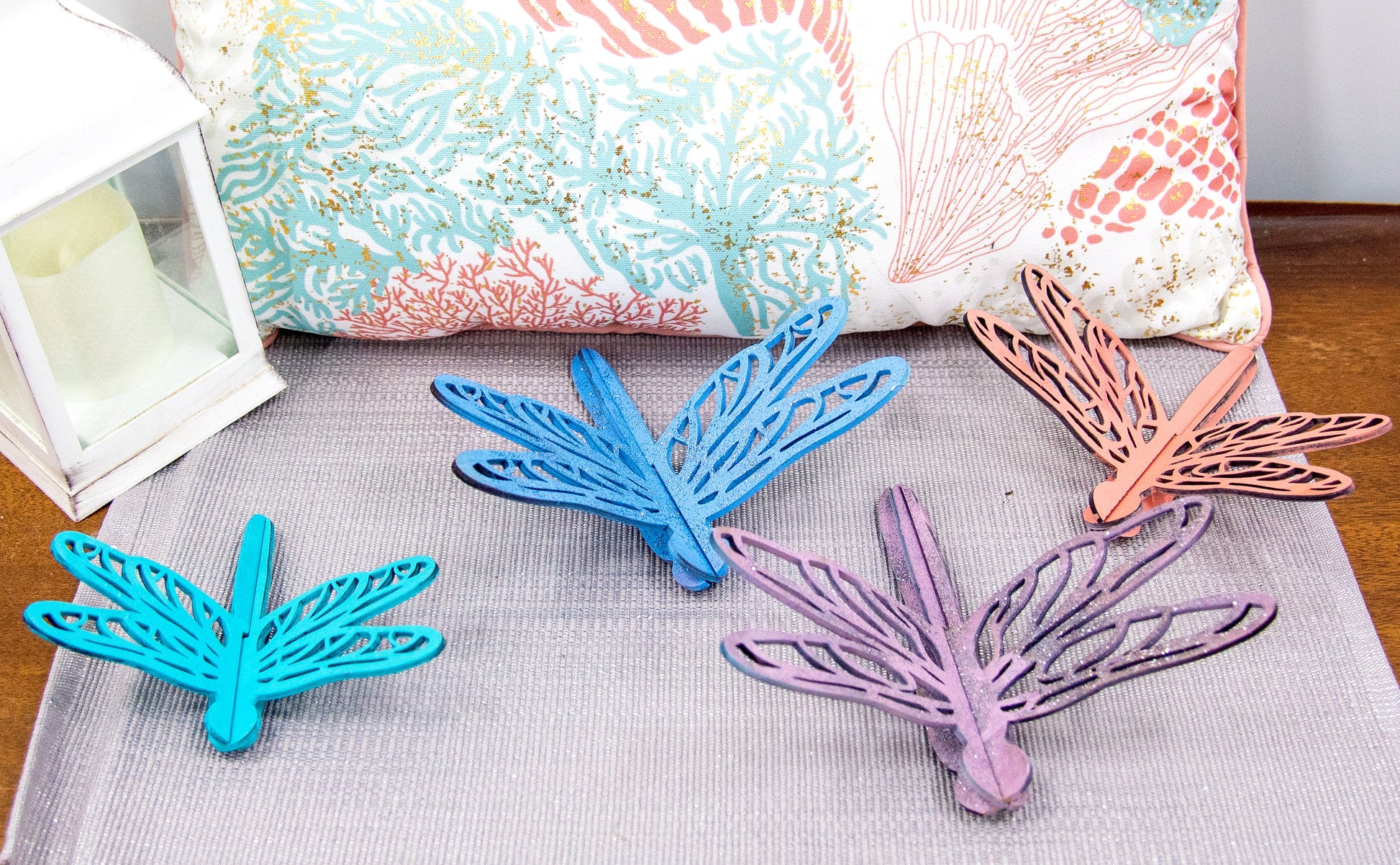 Colorful wooden dragonfly shelf sitters in rustic painted finishes, each shaped with wings and body details, perfect for whimsical spring or summer decor on mantels, shelves, or tiered trays.