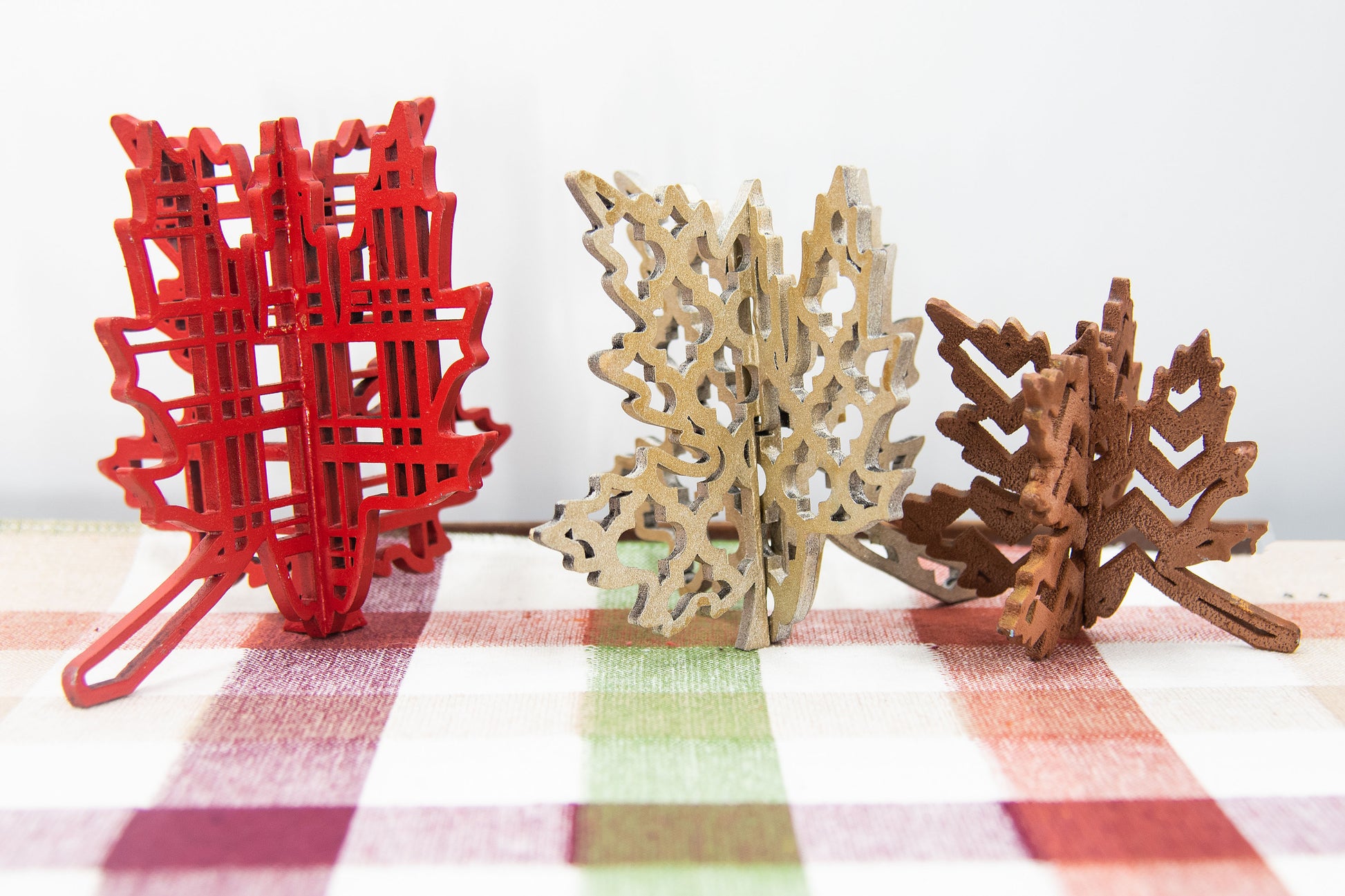 Freestanding 3D wooden leaf shelf sitters crafted with an interlocking two-piece design, painted in warm autumn colors such as orange, red, yellow, and brown. Each leaf features intricate engraved patterns and textures, making them perfect for seasonal tiered trays, mantels, or fall-themed centerpieces. Sizes range from 3 to 5.5 inches tall, with customizable color options for a unique, rustic autumn decor touch.
