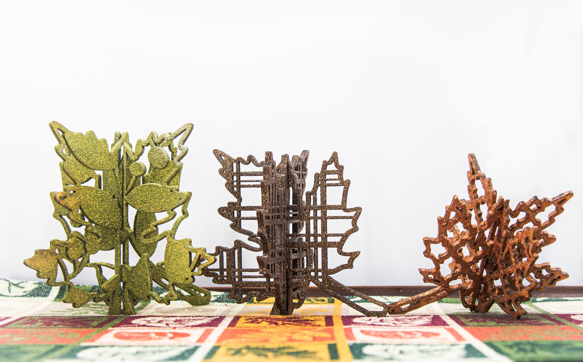 Freestanding 3D wooden leaf shelf sitters crafted with an interlocking two-piece design, painted in warm autumn colors such as orange, red, yellow, and brown. Each leaf features intricate engraved patterns and textures, making them perfect for seasonal tiered trays, mantels, or fall-themed centerpieces. Sizes range from 3 to 5.5 inches tall, with customizable color options for a unique, rustic autumn decor touch.
