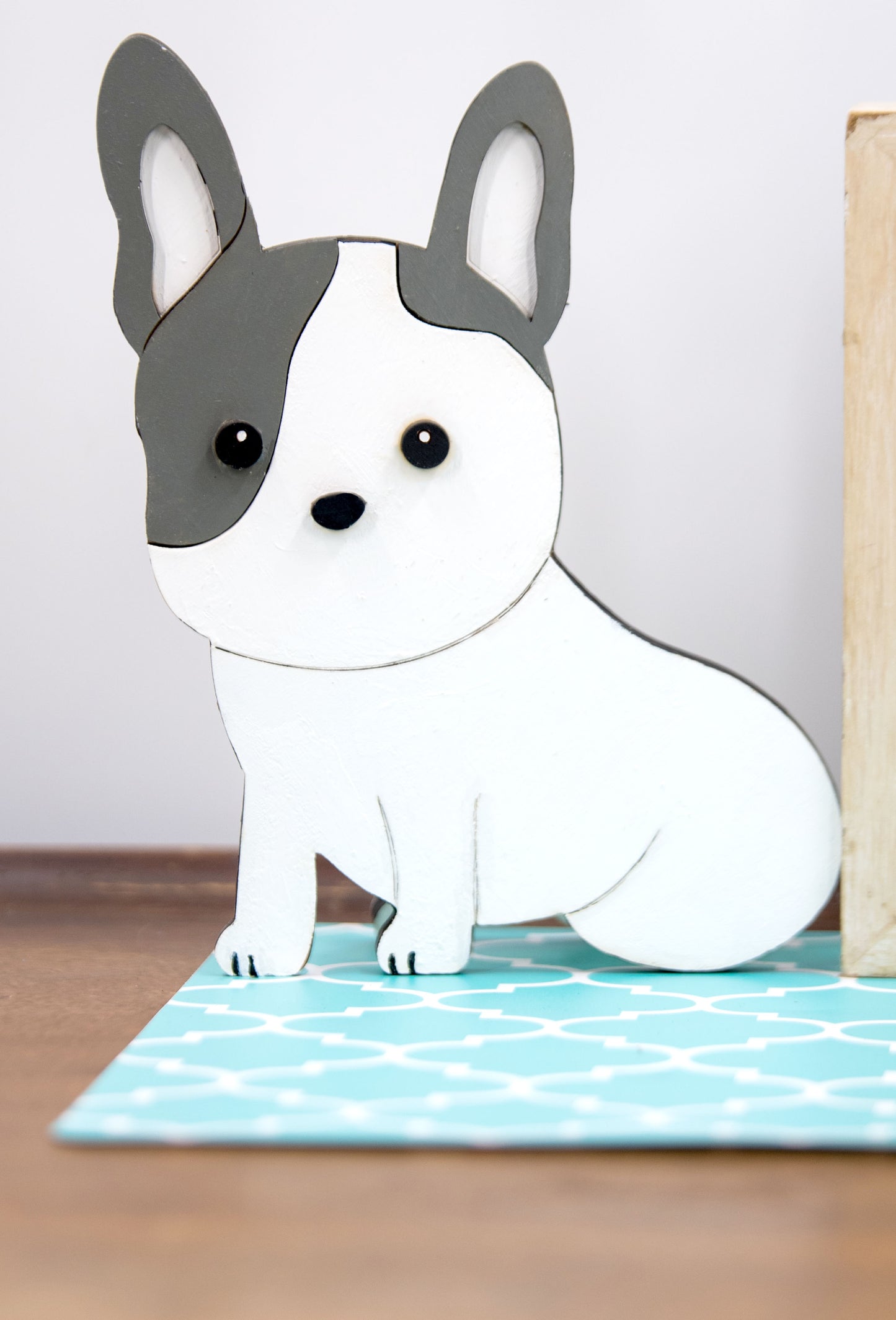 A hand-painted wooden glasses holder shaped like the face of a French Bulldog, featuring detailed ears, muzzle, and facial markings. The stand includes a flat base for stability and is designed to securely hold a pair of eyeglasses on the dog’s nose. Ideal as a decorative desk accessory, nightstand organizer, or pet-themed gift for Frenchie lovers.
