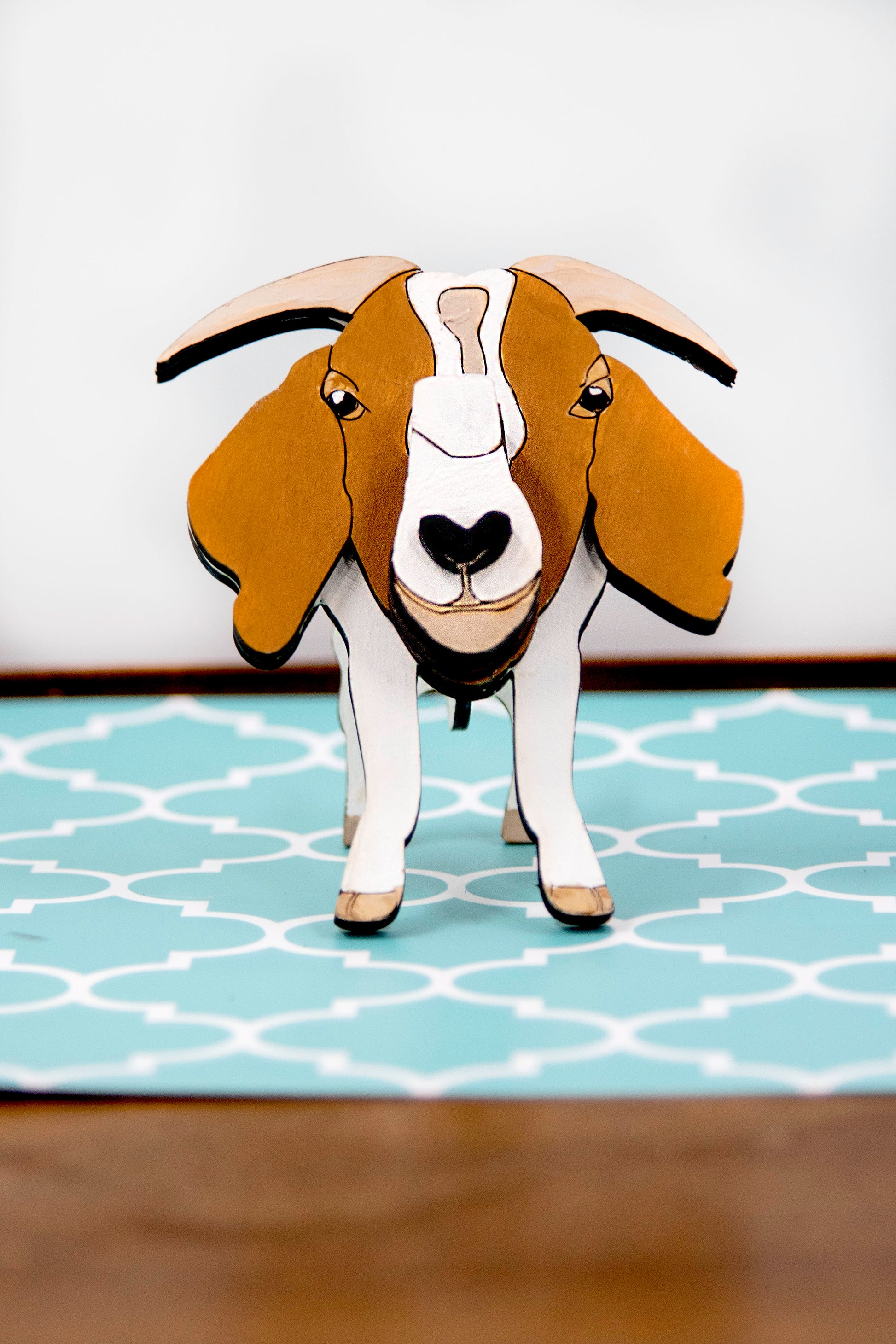Handcrafted wooden goat glasses holder featuring carved facial details, horns, and a sturdy snout to support eyeglasses. Painted in rustic tones, this charming eyeglass stand is perfect for goat enthusiasts, farmers, or anyone who loves quirky animal decor.