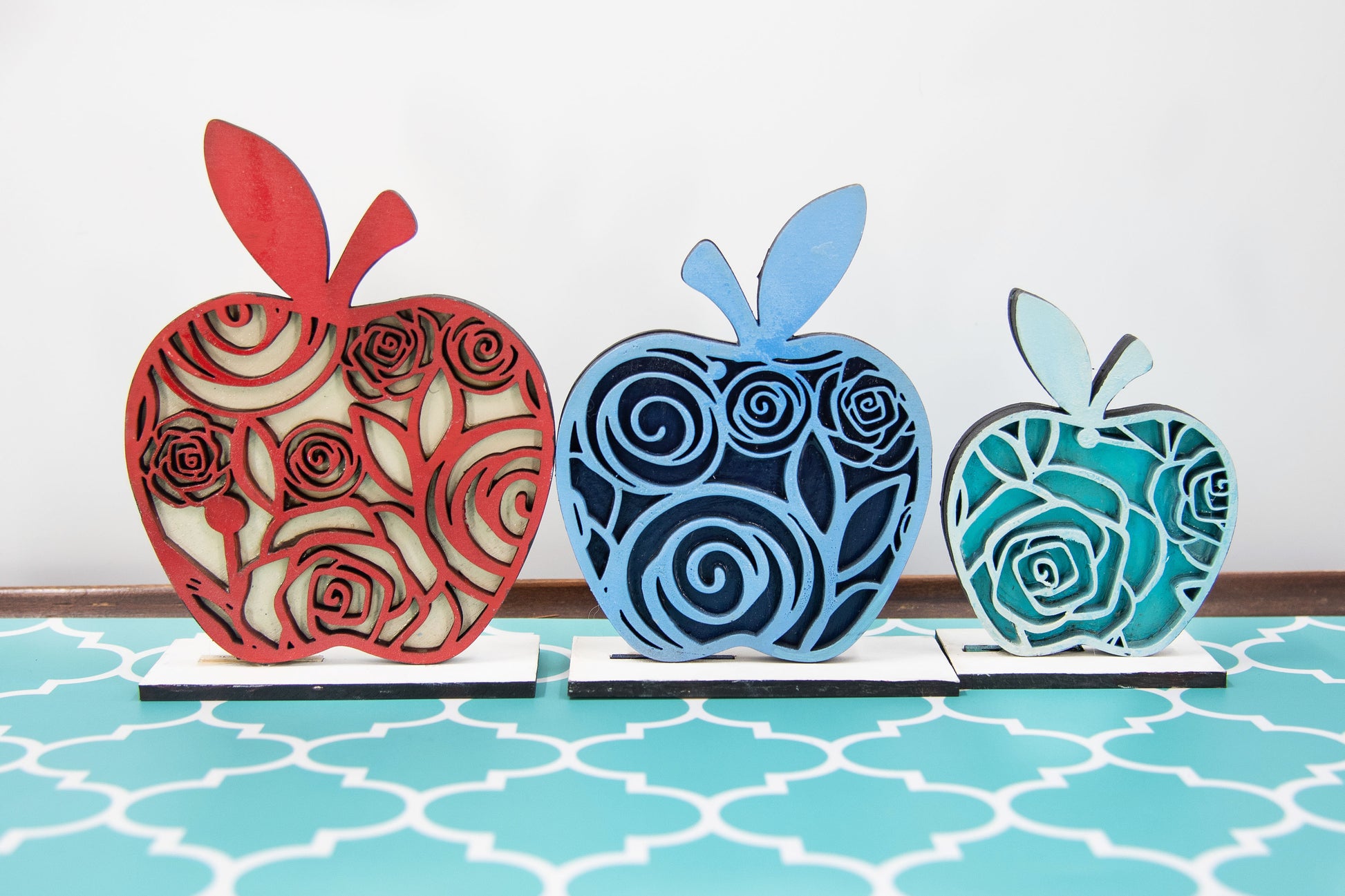 A handcrafted set of three standing wooden apple shelf sitters in assorted fall colors and patterns. These tiered tray-ready decorations include a rustic base and patterned top layer. Available individually or as a complete set, they bring warmth and charm to autumn home decor, classroom displays, or teacher gifts. Sizes range from 3.75" to 5.5".

