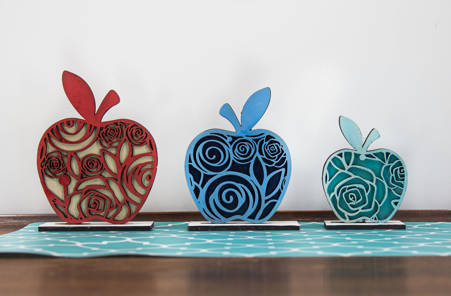 A handcrafted set of three standing wooden apple shelf sitters in assorted fall colors and patterns. These tiered tray-ready decorations include a rustic base and patterned top layer. Available individually or as a complete set, they bring warmth and charm to autumn home decor, classroom displays, or teacher gifts. Sizes range from 3.75" to 5.5".
