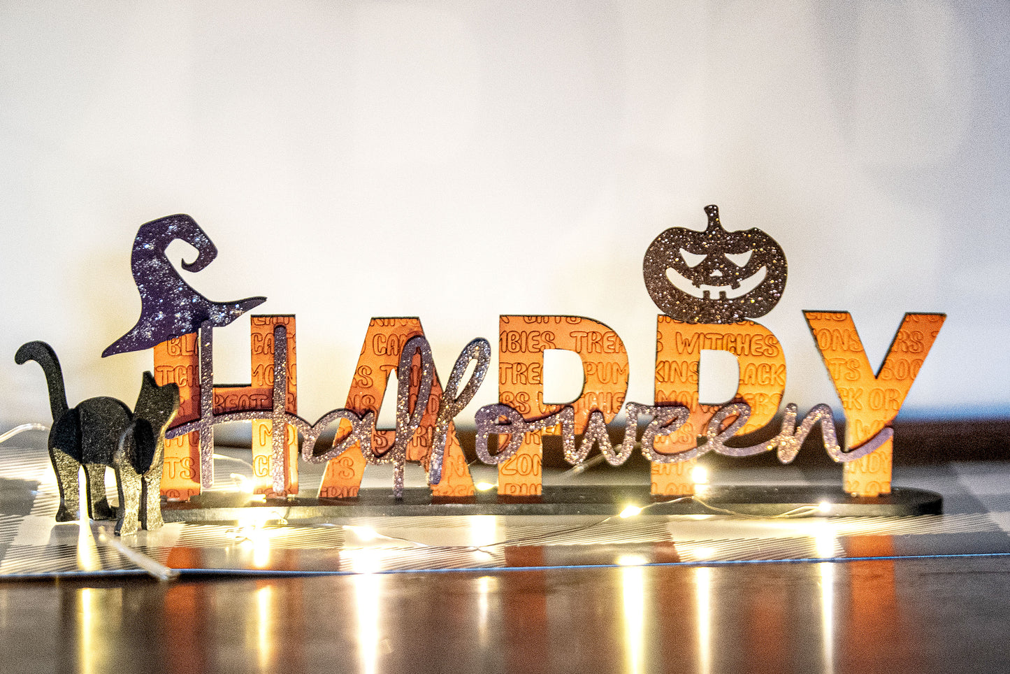 Happy Halloween wooden shelf sitter sign in festive spooky colors, laser-cut layered wood, free-standing design for mantels, shelves, or tiered tray fall decor.

