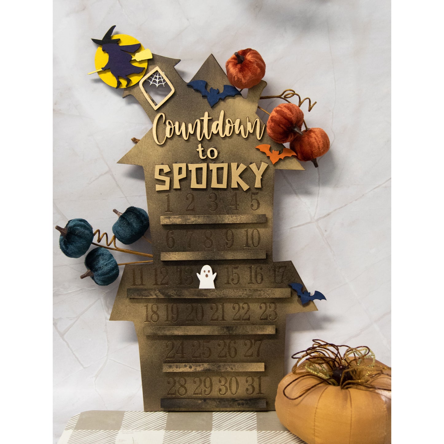 Wooden haunted house-themed Halloween countdown sign with engraved numbers from 1 to 31, painted in classic spooky colors like black, orange, and purple. Features a large haunted mansion design with bats, ghosts, and interchangeable marker icons to track the days until Halloween. Freestanding and available in two sizes, this layered wood sign is perfect for holiday decorating on a mantel, entryway, or shelf display.
