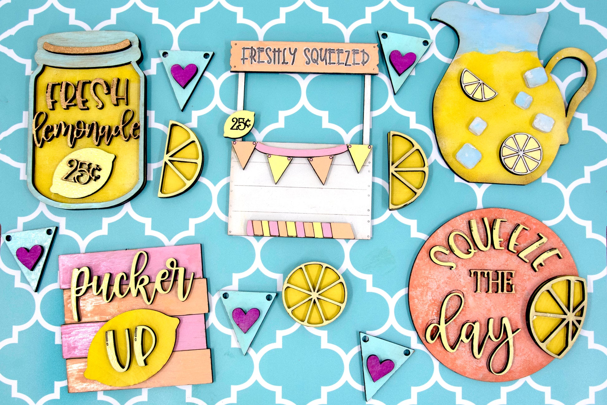 Hand-painted lemonade-themed tiered tray set featuring five wooden decor pieces in pastel pink, yellow, and orange. Includes lemon slice accents, banner flags, and stands for each item. Optional matching wooden tray base available