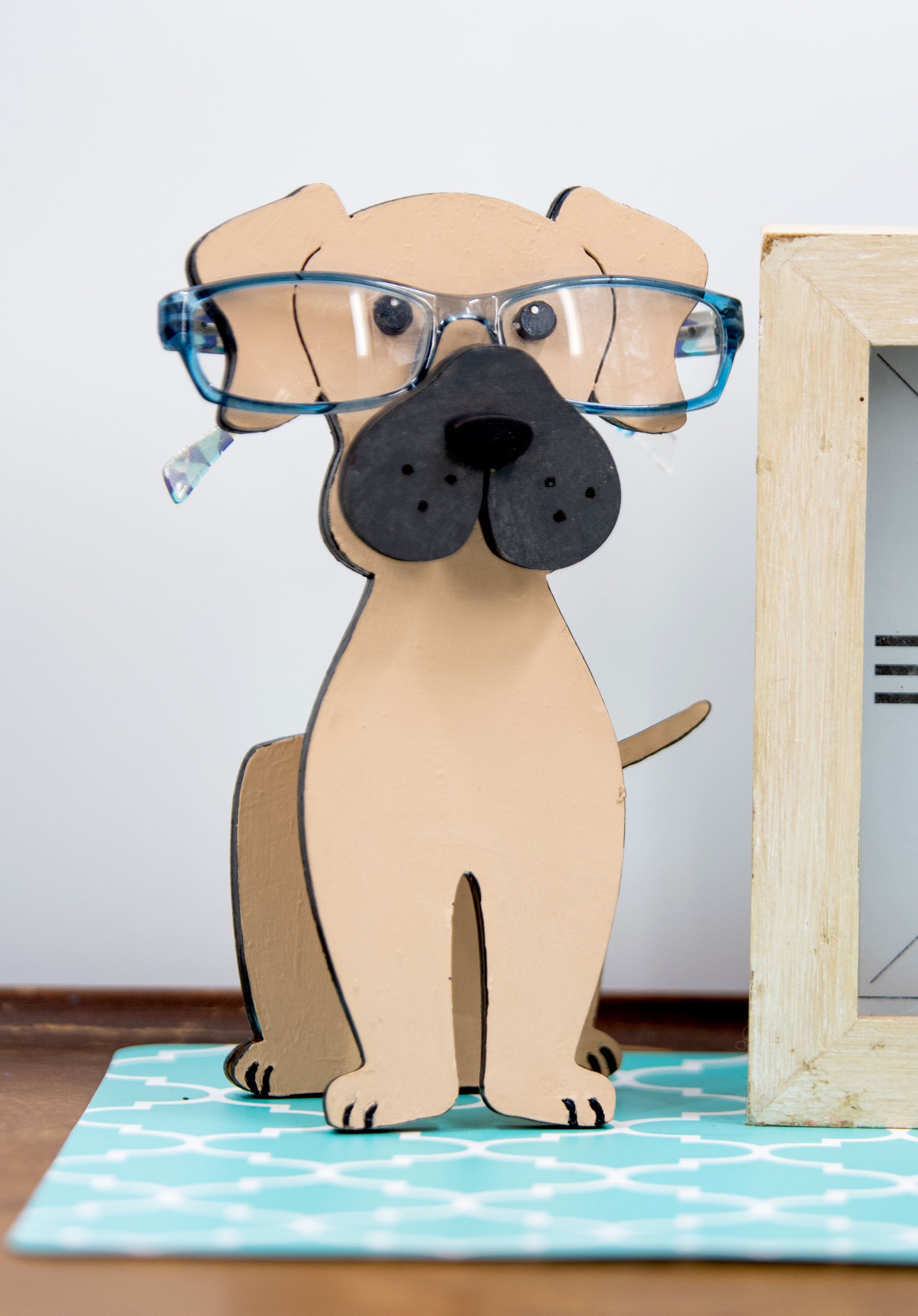 Handmade wooden glasses holder shaped like a Mastiff dog, featuring carved facial details and a sturdy snout that securely holds eyeglasses. Finished in rustic tones with optional personalization, this stand is perfect for Mastiff lovers and adds charm and function to any desk, nightstand, or shelf.