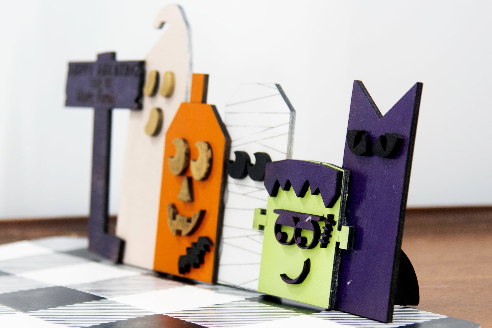 Layered wooden Halloween character shelf sitter set featuring Frankenstein, ghost, black cat, pumpkin, and tombstone. Includes interchangeable face designs, personalized sign text, and multiple size options for Halloween home decor.