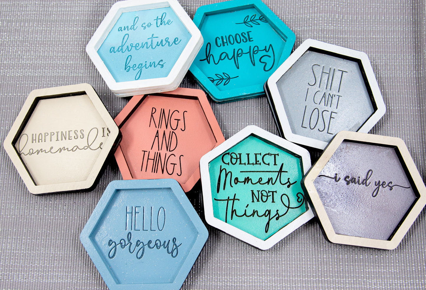 Set of small 3.75-inch round wooden trinket dishes available in various bright colors, each engraved with playful or inspiring sayings like 'Choose Happy,' 'Shit I Can’t Lose,' and 'Collect Moments Not Things.' These colorful dishes work perfectly as jewelry holders, desk catch-alls, or thoughtful gifts