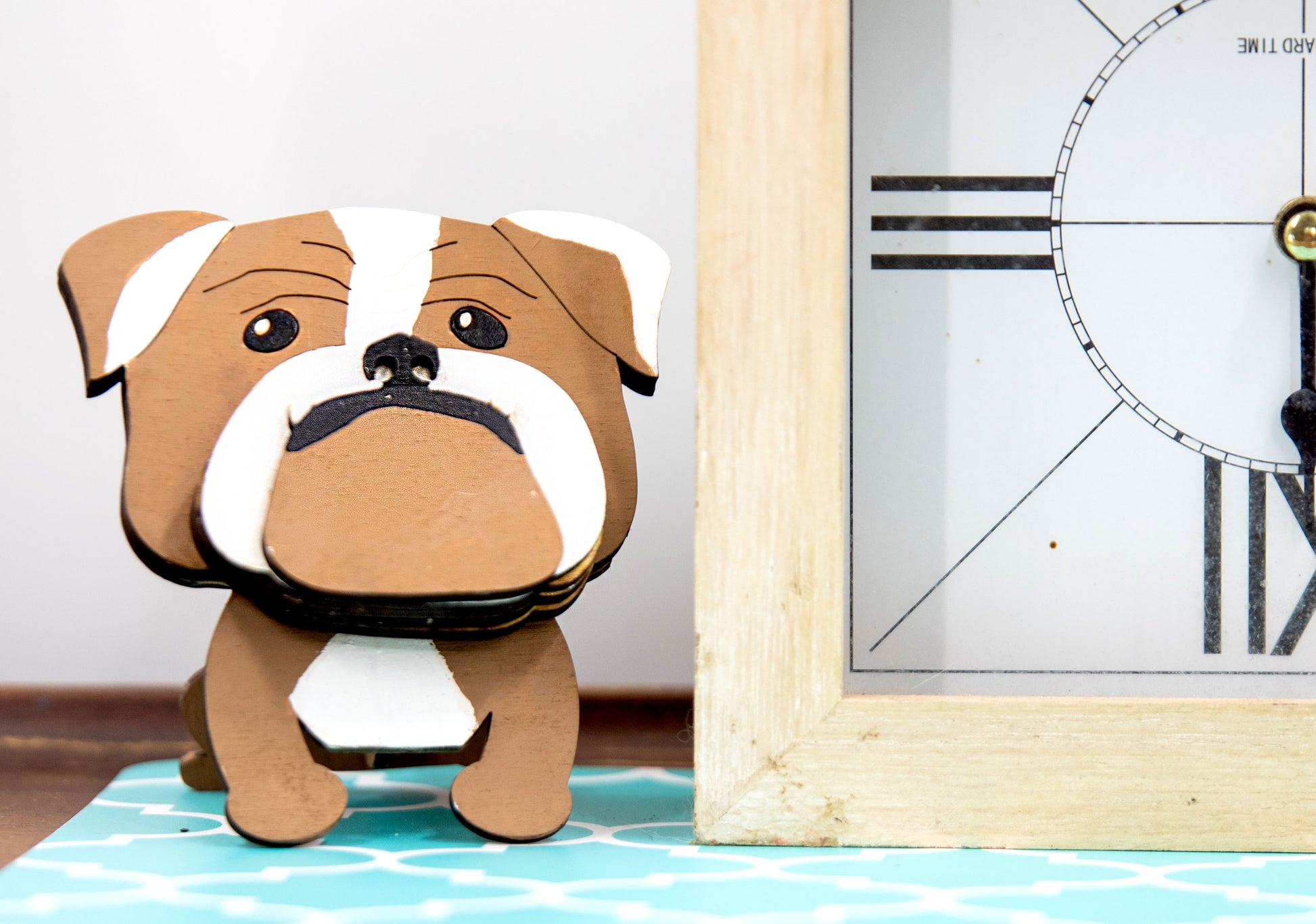 A hand-painted wooden glasses stand shaped like the face of an English Bulldog, featuring the breed’s signature wrinkled face and droopy cheeks. Designed with a flat base for stability, the stand holds eyeglasses securely on the Bulldog’s nose, making it a functional and charming decor piece for desks, nightstands, or shelves.