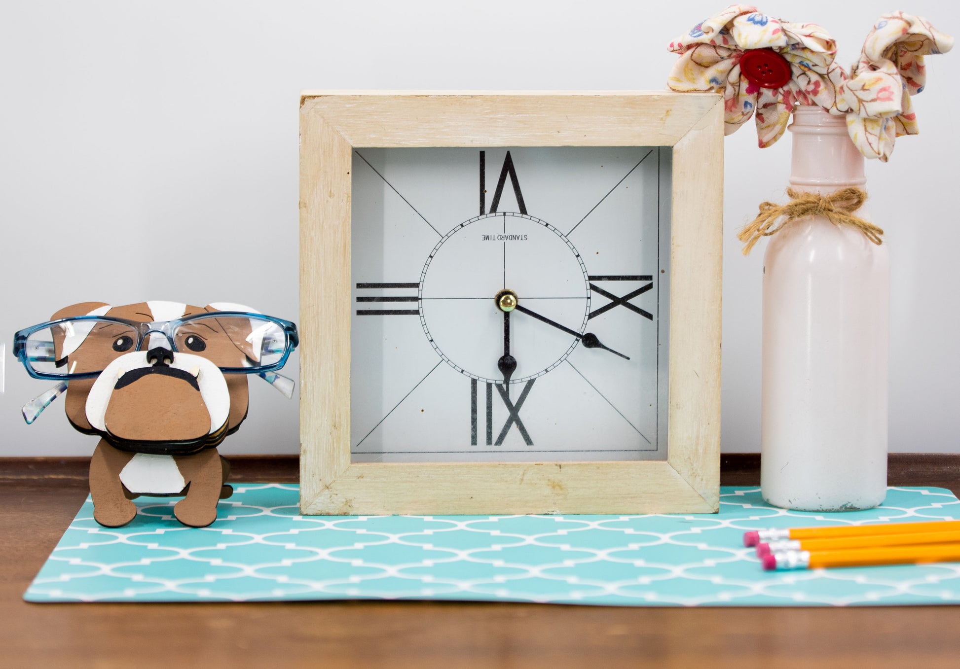 A hand-painted wooden glasses stand shaped like the face of an English Bulldog, featuring the breed’s signature wrinkled face and droopy cheeks. Designed with a flat base for stability, the stand holds eyeglasses securely on the Bulldog’s nose, making it a functional and charming decor piece for desks, nightstands, or shelves.