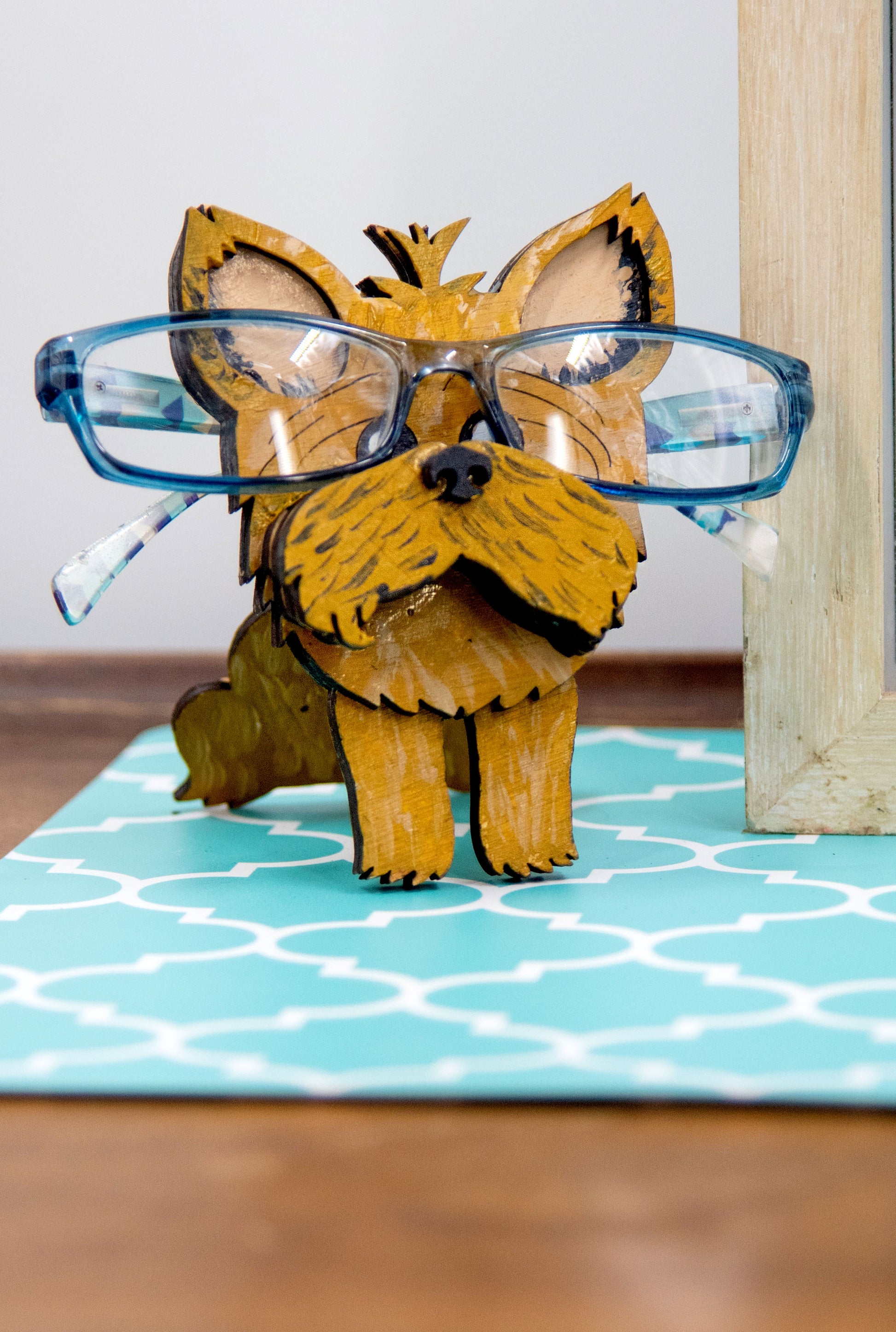 Hand-painted wooden glasses holder shaped like a Yorkshire Terrier with signature silky fur and upright ears, designed to hold eyeglasses on its face. Perfect for Yorkie lovers