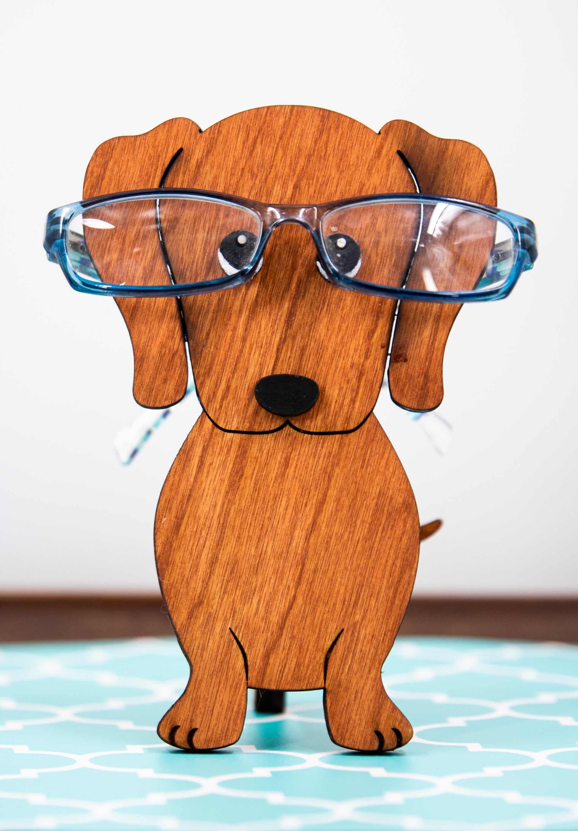 Large stained dachshund glasses holder made from solid wood, shown in red/brown finish, designed to keep eyeglasses secure while adding charm to your decor. Handmade eyeglass stand shaped like a dachshund with adorable detailing, perfect for bedside tables, desks, or as a thoughtful gift for dog lovers. Available in red/brown, black, or custom stain colors to match your style.