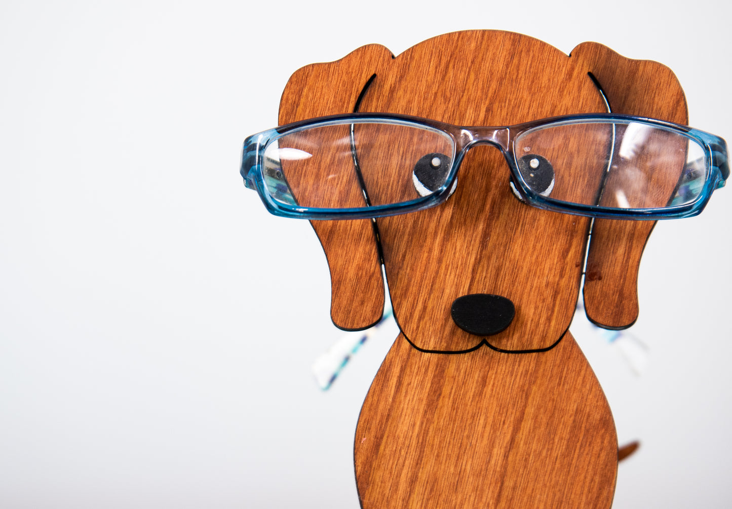 Large stained dachshund glasses holder made from solid wood, shown in red/brown finish, designed to keep eyeglasses secure while adding charm to your decor. Handmade eyeglass stand shaped like a dachshund with adorable detailing, perfect for bedside tables, desks, or as a thoughtful gift for dog lovers. Available in red/brown, black, or custom stain colors to match your style.