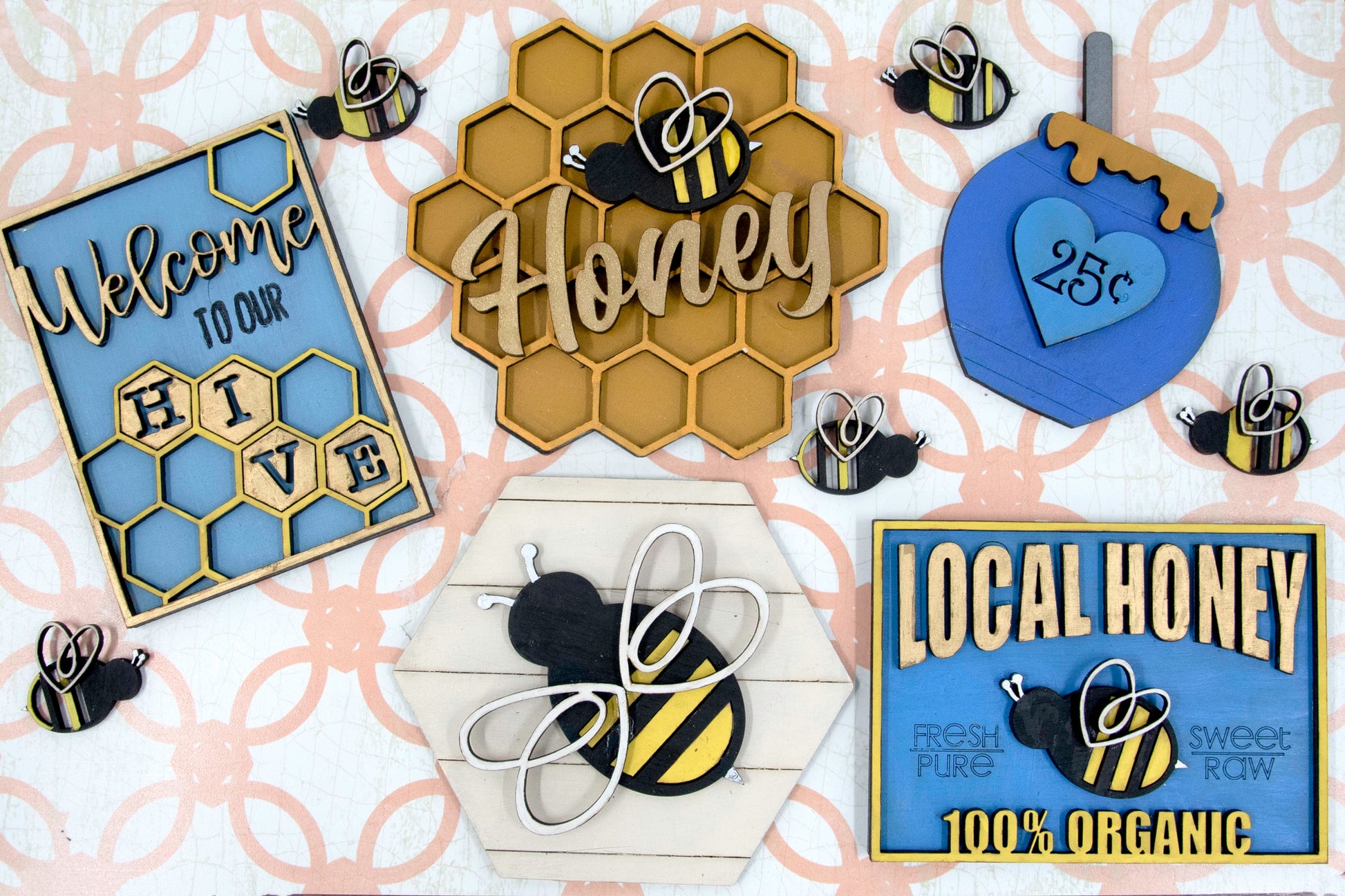 DIY bee tiered tray kit with 6 unfinished wood pieces including honey jar, local honey sign, welcome to our hive sign, honey bomb, bee hexagon plaque, and 5 small bee accents. Ideal for painting, staining, and customizing. Comes with stands for easy display. Perfect for summer crafts, farmhouse style decor, or paint-your-own projects. Great for hobby crafters, DIY parties, and seasonal decorating fun with a bee and honey theme.
