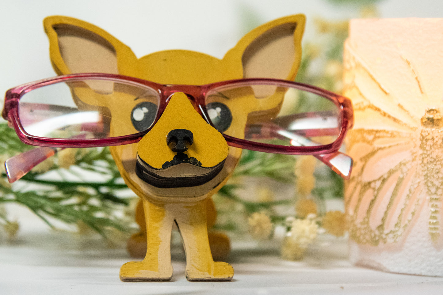 Hand-painted wooden chihuahua glasses holder shaped like a small standing dog, designed to hold eyeglasses securely on its nose. Features custom-painted colors like black, tan, or white. Functional dog decor that works as an eyeglass organizer for pet lovers, dog moms, or anyone who adores their chihuahua. Made from wood and painted by hand with charming detail, ideal for display on desks, nightstands, or bookshelves.