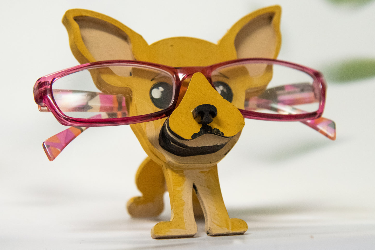Hand-painted wooden chihuahua glasses holder shaped like a small standing dog, designed to hold eyeglasses securely on its nose. Features custom-painted colors like black, tan, or white. Functional dog decor that works as an eyeglass organizer for pet lovers, dog moms, or anyone who adores their chihuahua. Made from wood and painted by hand with charming detail, ideal for display on desks, nightstands, or bookshelves.