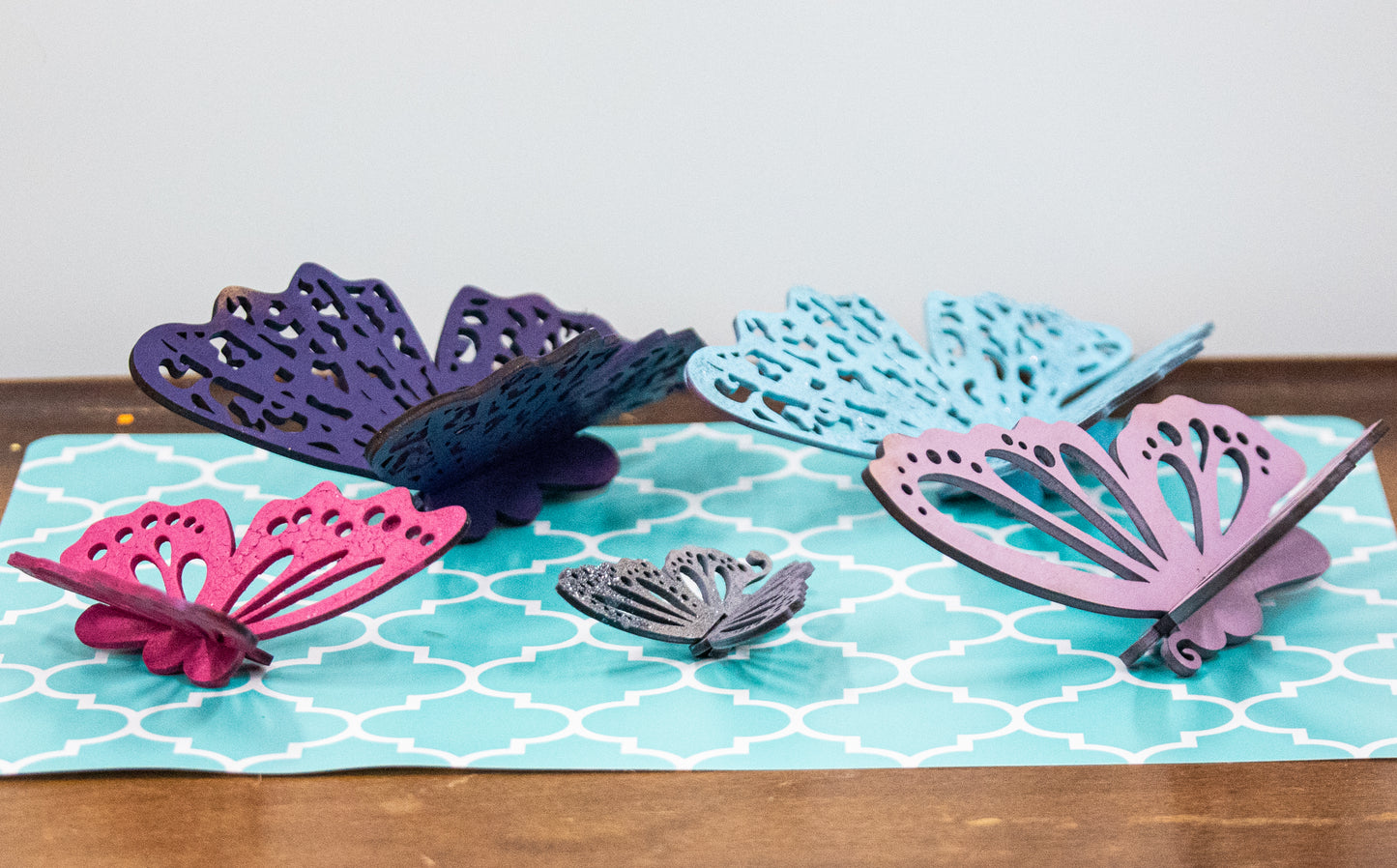 Finished 3D butterfly shelf sitter with two layers of wood, patterned top layer, hand painted in custom colors, standing on a shelf or tray as whimsical spring or seasonal decor accent.