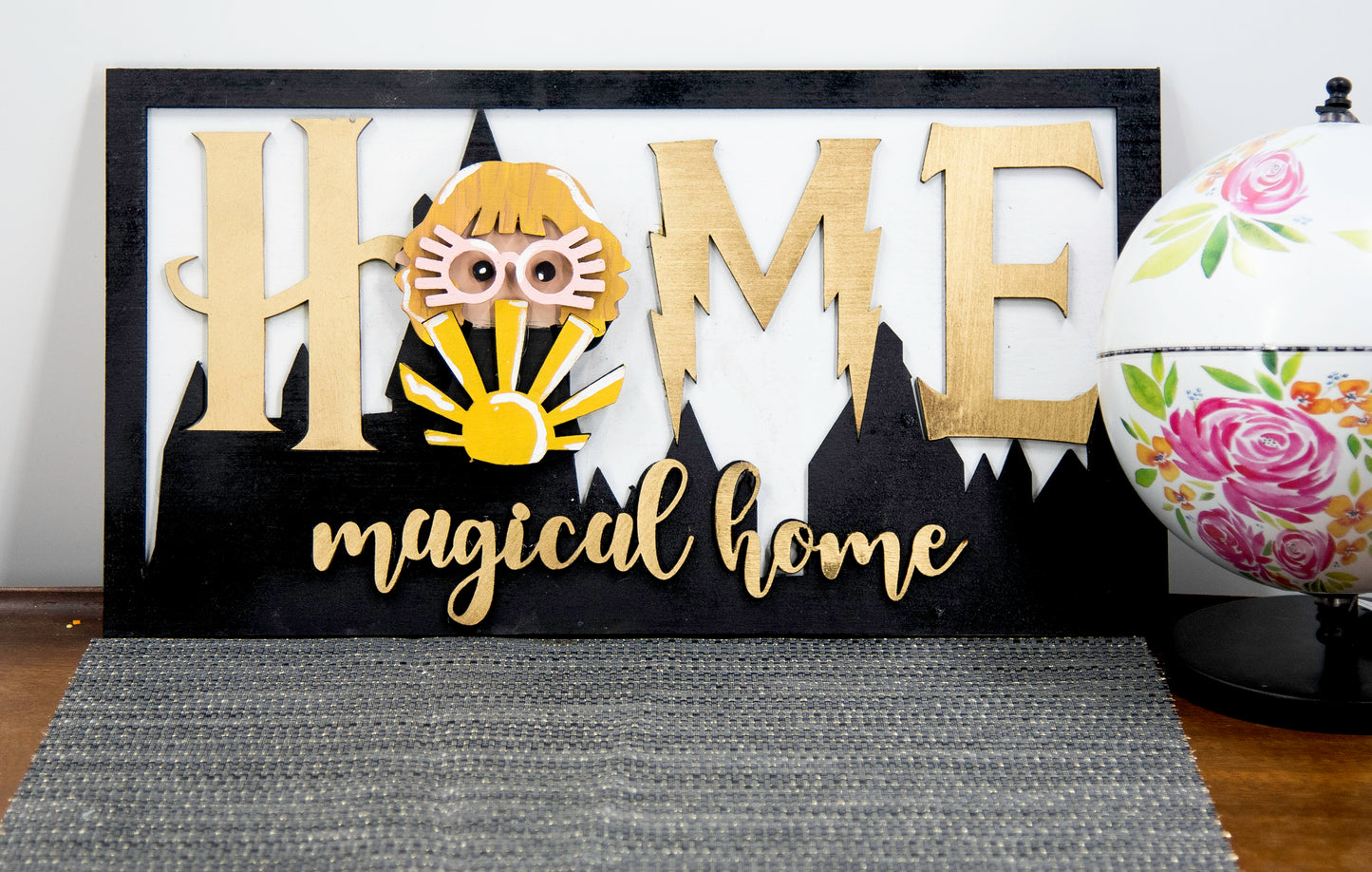 Full view of handcrafted wizard-themed interchangeable wooden sign that reads 'Home Magical Home' with wizard silhouettes forming the letter O, displayed on a shelf with all 12 hand-painted seasonal pieces including pumpkin, snowflake, shamrock, heart, sun, watermelon, leaf, ornament, egg, flower, flag, and candy corn — perfect for year-round magical home decor, Harry Potter-inspired, fantasy cottagecore aesthetic, unique seasonal gift for wizard fans and DIY crafters
