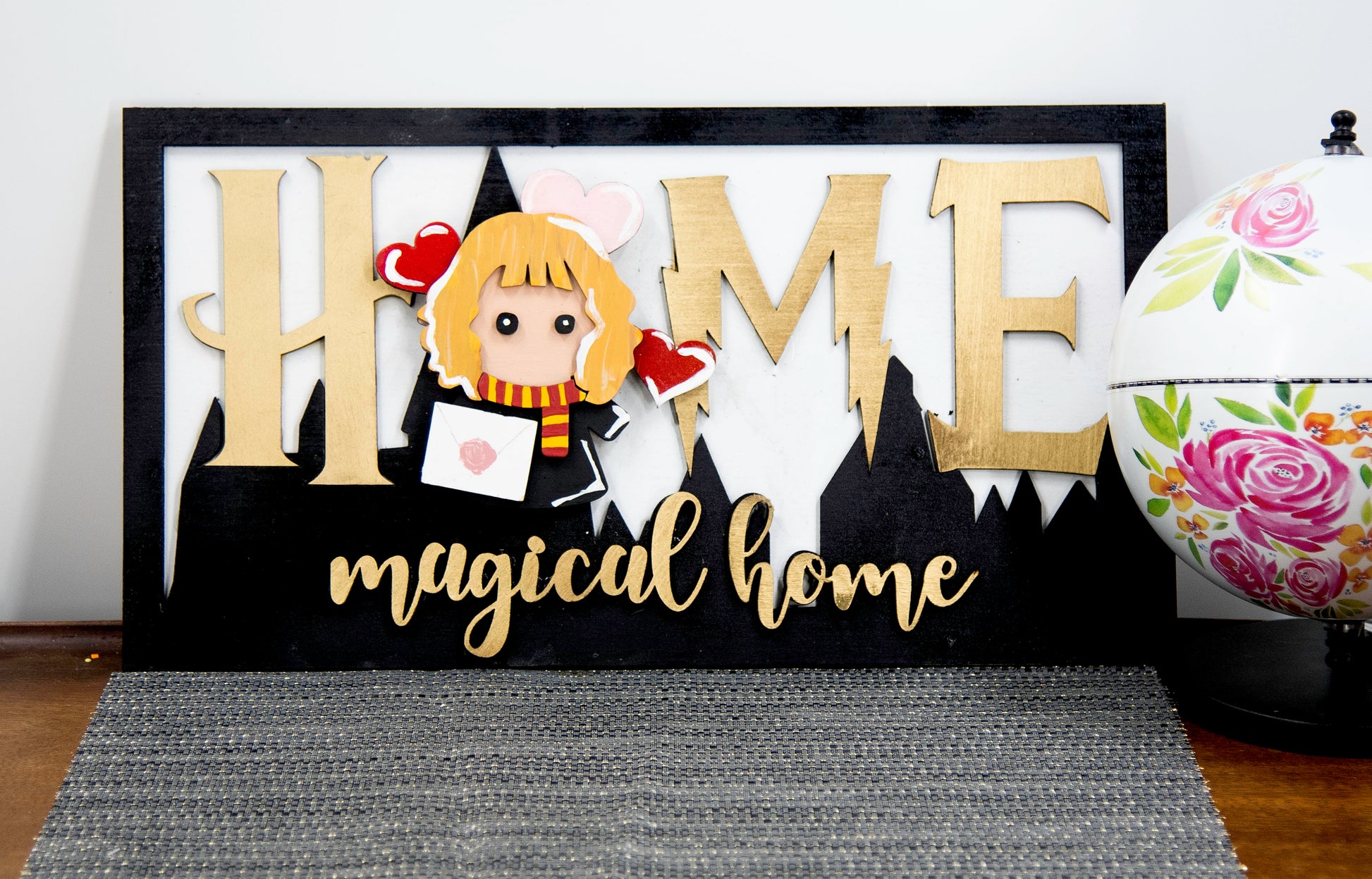 Full view of handcrafted wizard-themed interchangeable wooden sign that reads 'Home Magical Home' with wizard silhouettes forming the letter O, displayed on a shelf with all 12 hand-painted seasonal pieces including pumpkin, snowflake, shamrock, heart, sun, watermelon, leaf, ornament, egg, flower, flag, and candy corn — perfect for year-round magical home decor, Harry Potter-inspired, fantasy cottagecore aesthetic, unique seasonal gift for wizard fans and DIY crafters