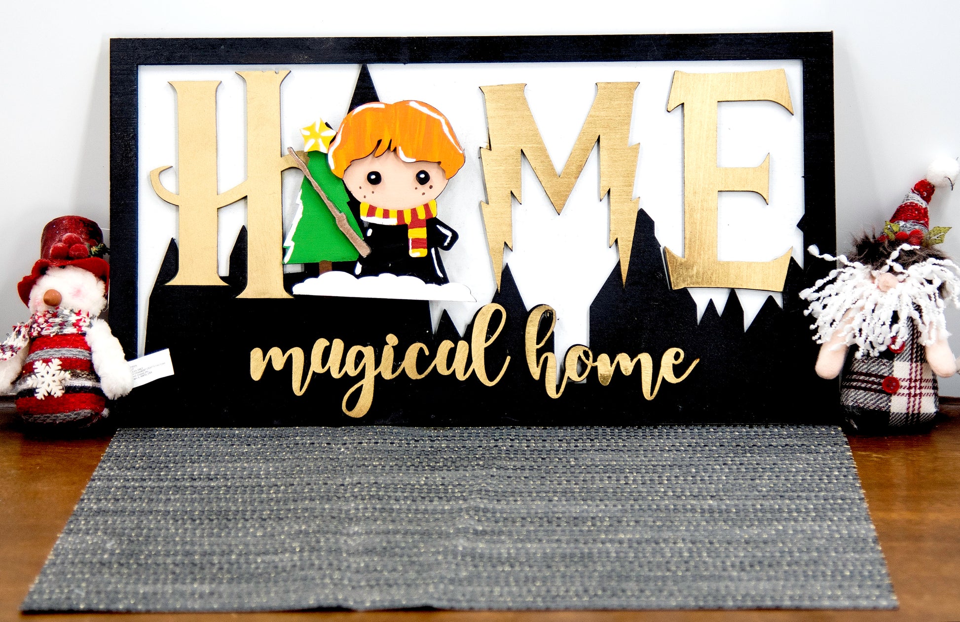 Full view of handcrafted wizard-themed interchangeable wooden sign that reads 'Home Magical Home' with wizard silhouettes forming the letter O, displayed on a shelf with all 12 hand-painted seasonal pieces including pumpkin, snowflake, shamrock, heart, sun, watermelon, leaf, ornament, egg, flower, flag, and candy corn — perfect for year-round magical home decor, Harry Potter-inspired, fantasy cottagecore aesthetic, unique seasonal gift for wizard fans and DIY crafters