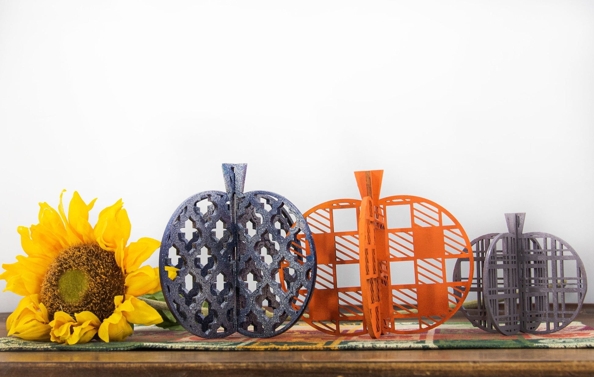 Set of handcrafted 3D wooden pumpkins in fall colors with interlocking design, standing upright for tiered trays or shelf decor, available in custom or traditional autumn tones.
