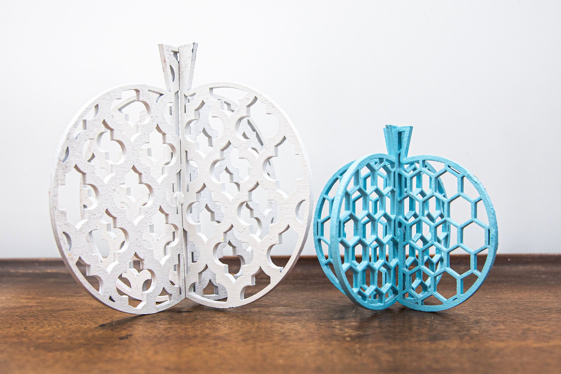 Set of handcrafted 3D wooden pumpkins in fall colors with interlocking design, standing upright for tiered trays or shelf decor, available in custom or traditional autumn tones.
